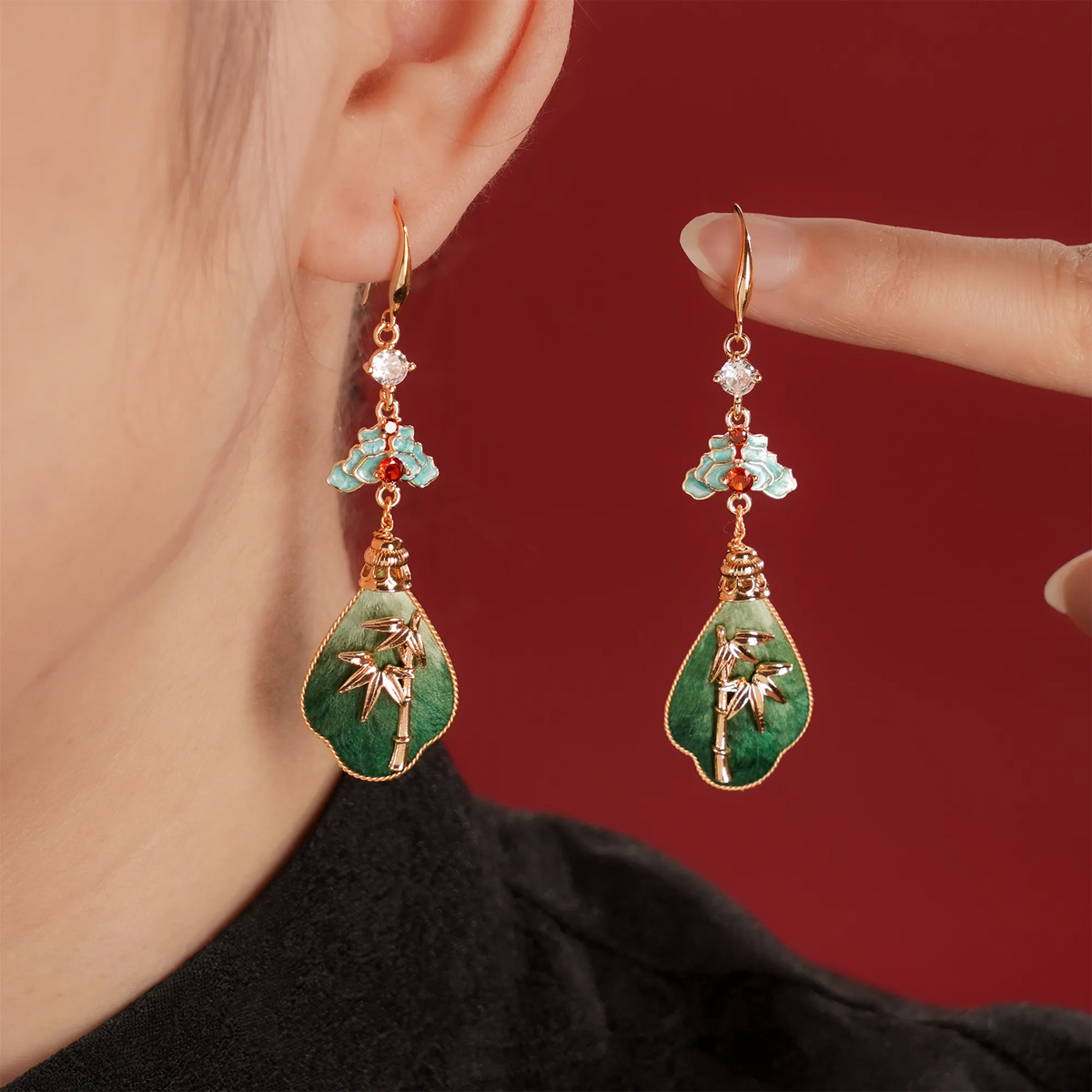 Model wearing green bamboo silk velvet drop earrings with gold-tone bamboo motifs
