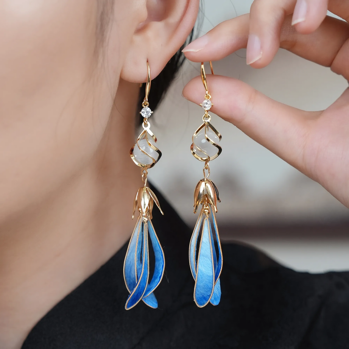 Blue magnolia silk velvet drop earrings worn by a model
