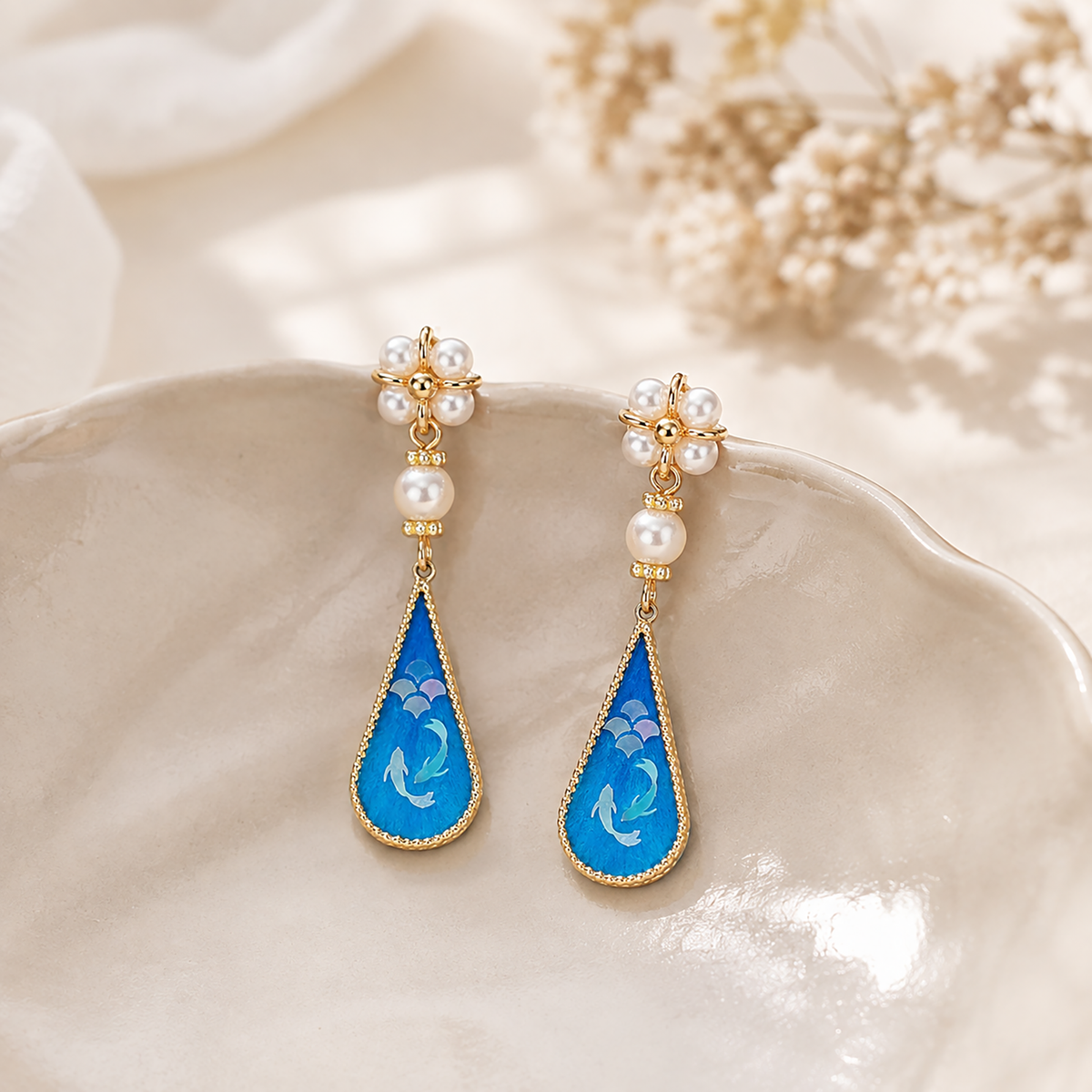 Twin fish silk velvet drop earrings displayed on ivory silk