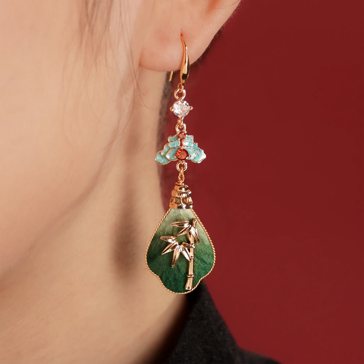 Close-up of a green bamboo silk velvet drop earring worn at the ear