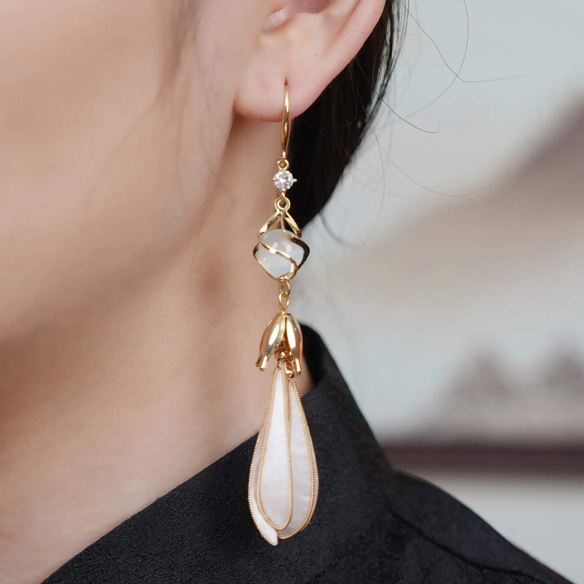 Close-up of long white magnolia silk velvet earrings being worn