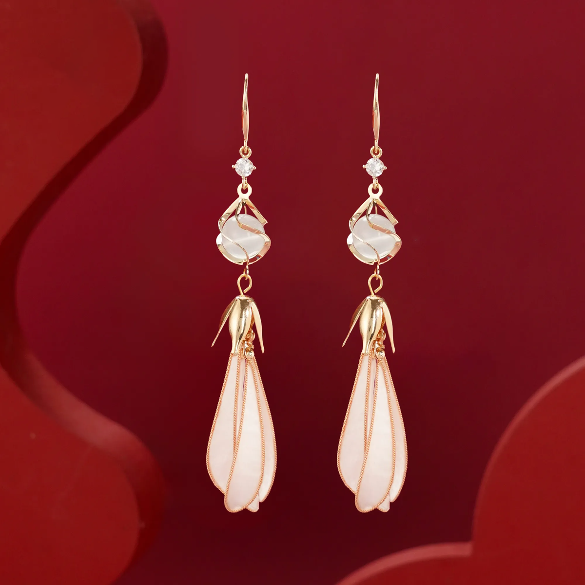 Front view of white magnolia silk velvet drop earrings on red