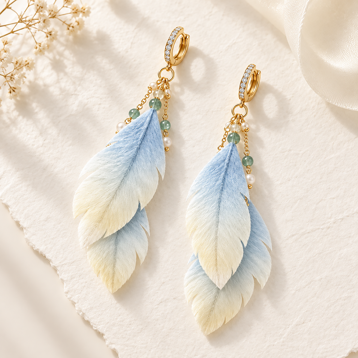 Pair of layered blue-to-ivory silk-fibre drop earrings on textured paper