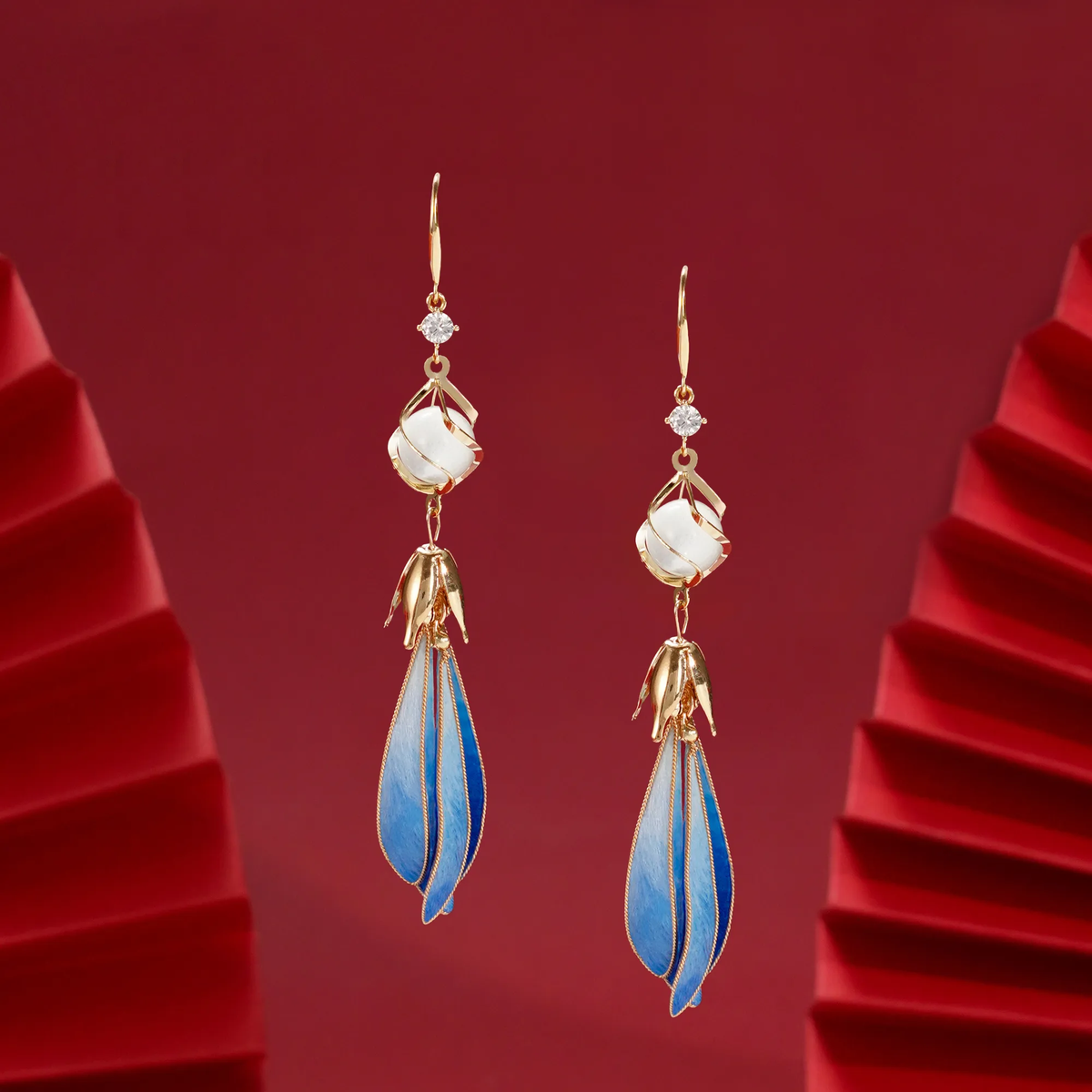 Angled view of blue magnolia silk velvet earrings showing gold-tone edging