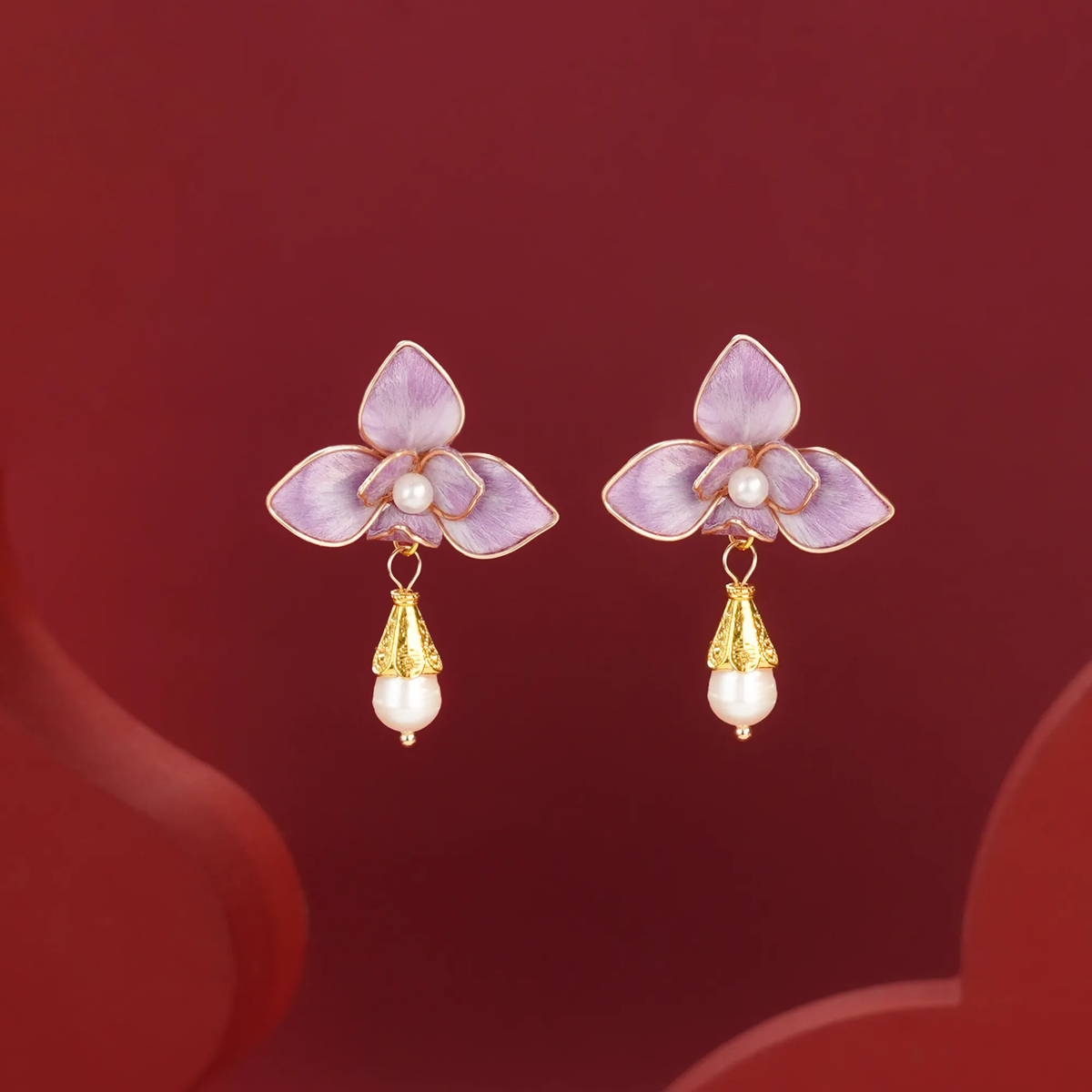 Front view of purple butterfly orchid earrings on red