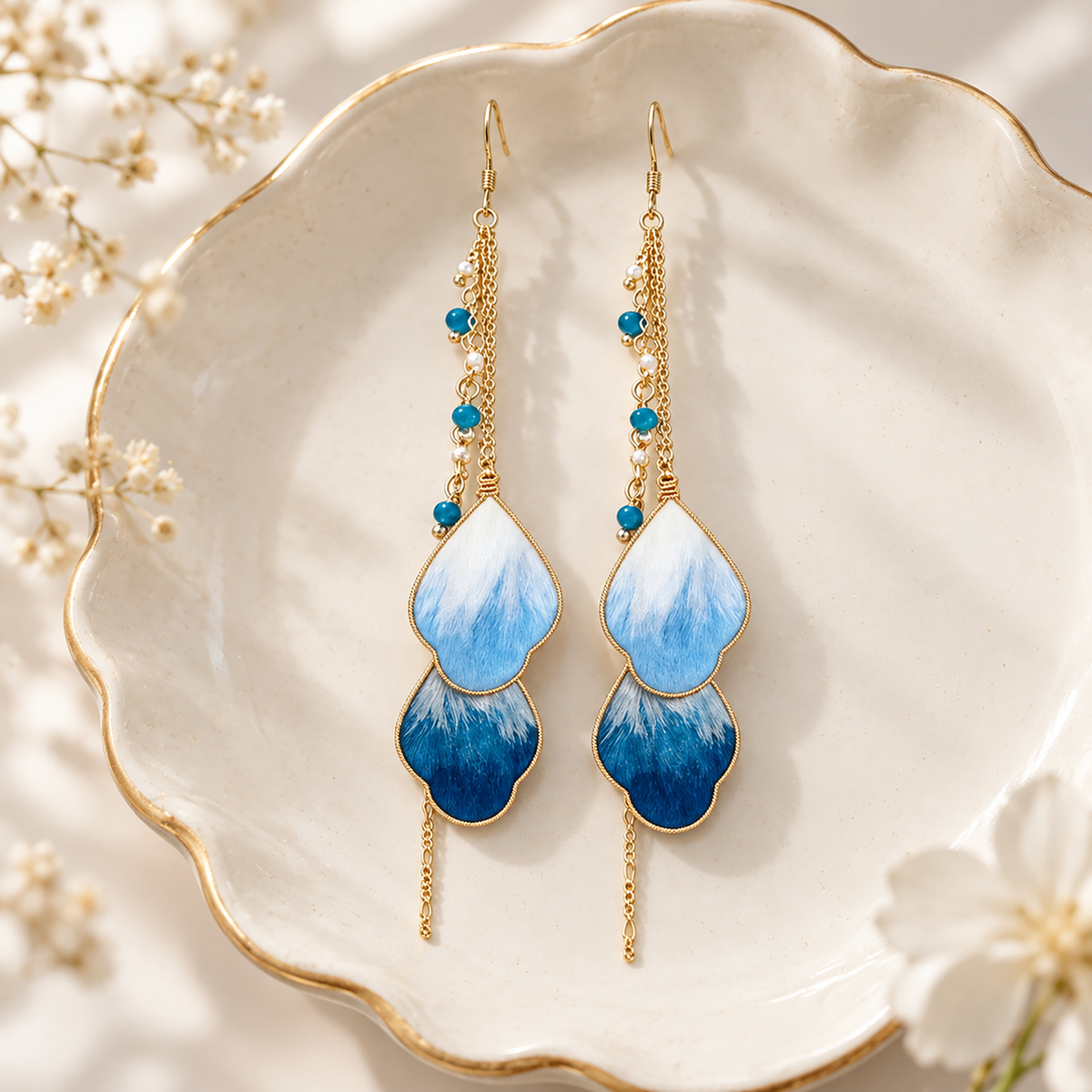 Blue vine silk drop earrings with fishhook wires lying in a cream dish