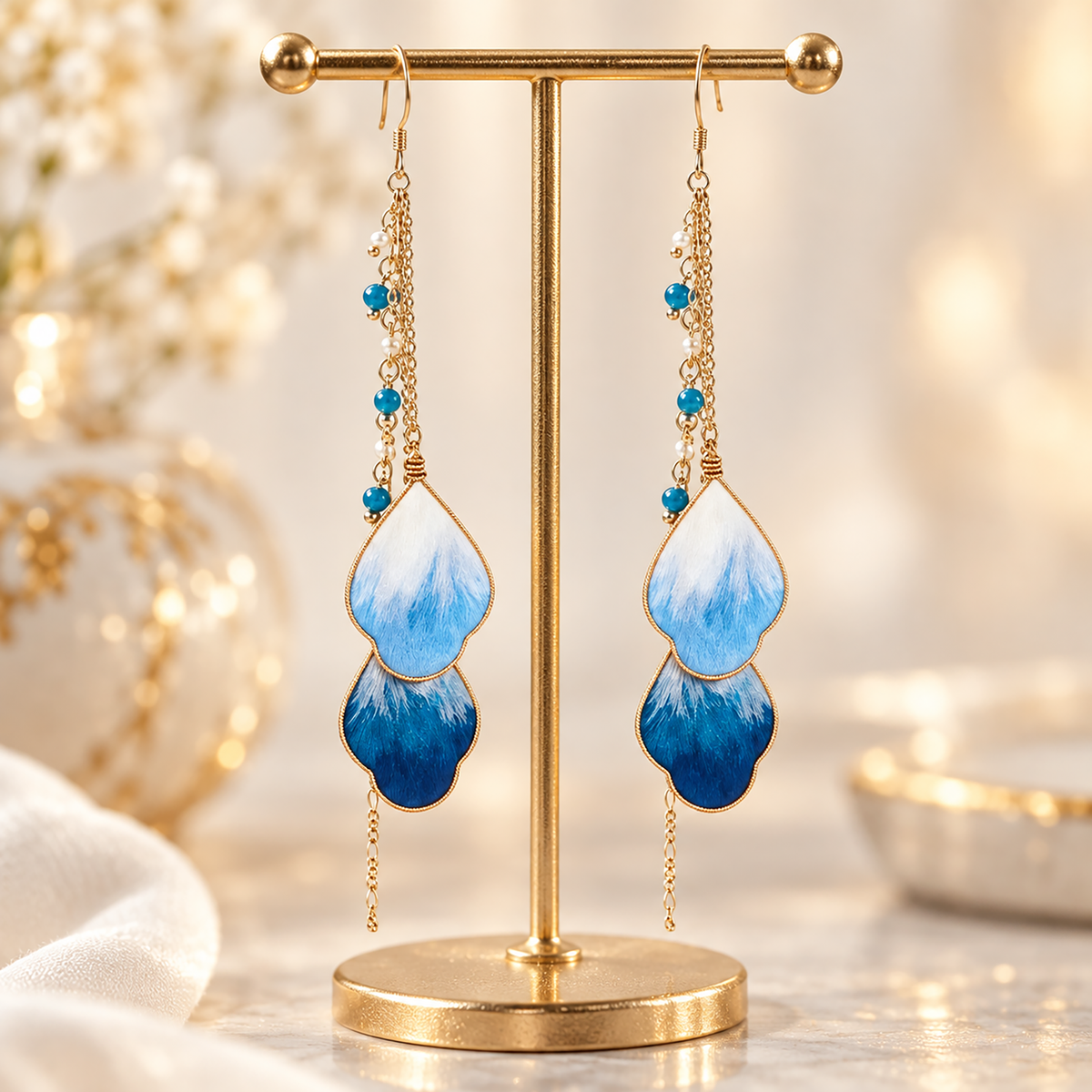Blue vine silk Ronghua drop earrings hanging from a display stand, fishhook wires and two stacked petals visible