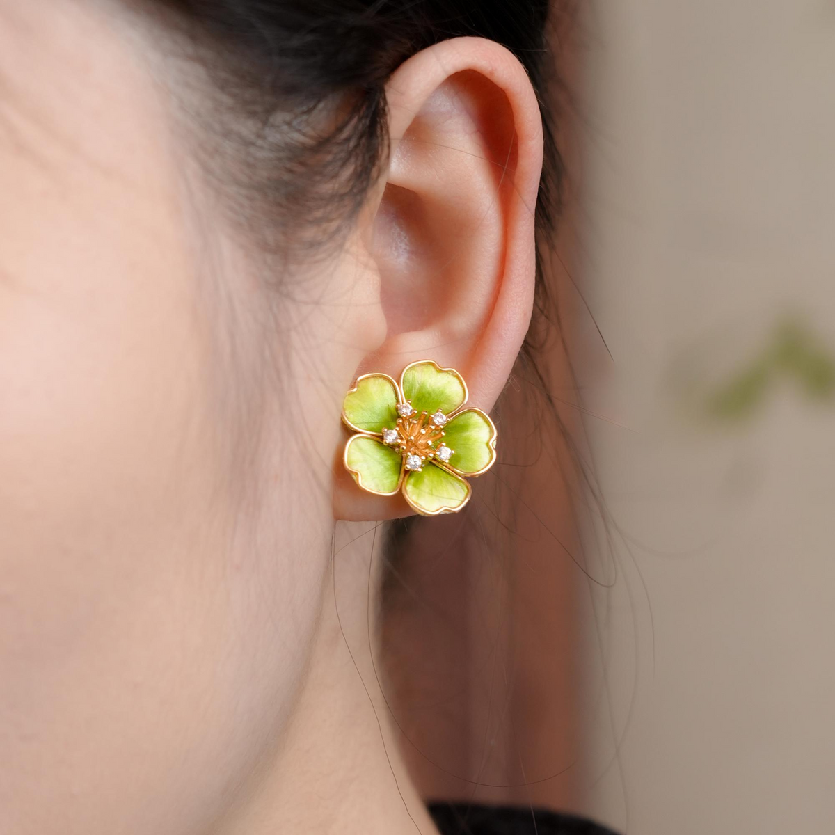 Close-up of a Spring Blossom green flower stud earring worn on ear