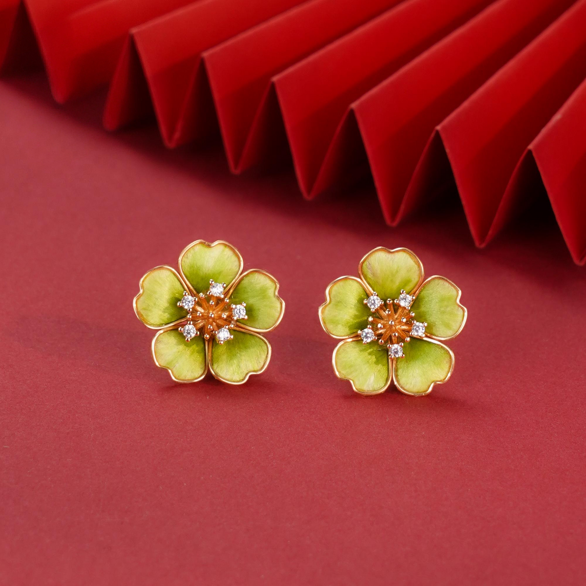 Front view of a pair of green floral stud earrings on a red background