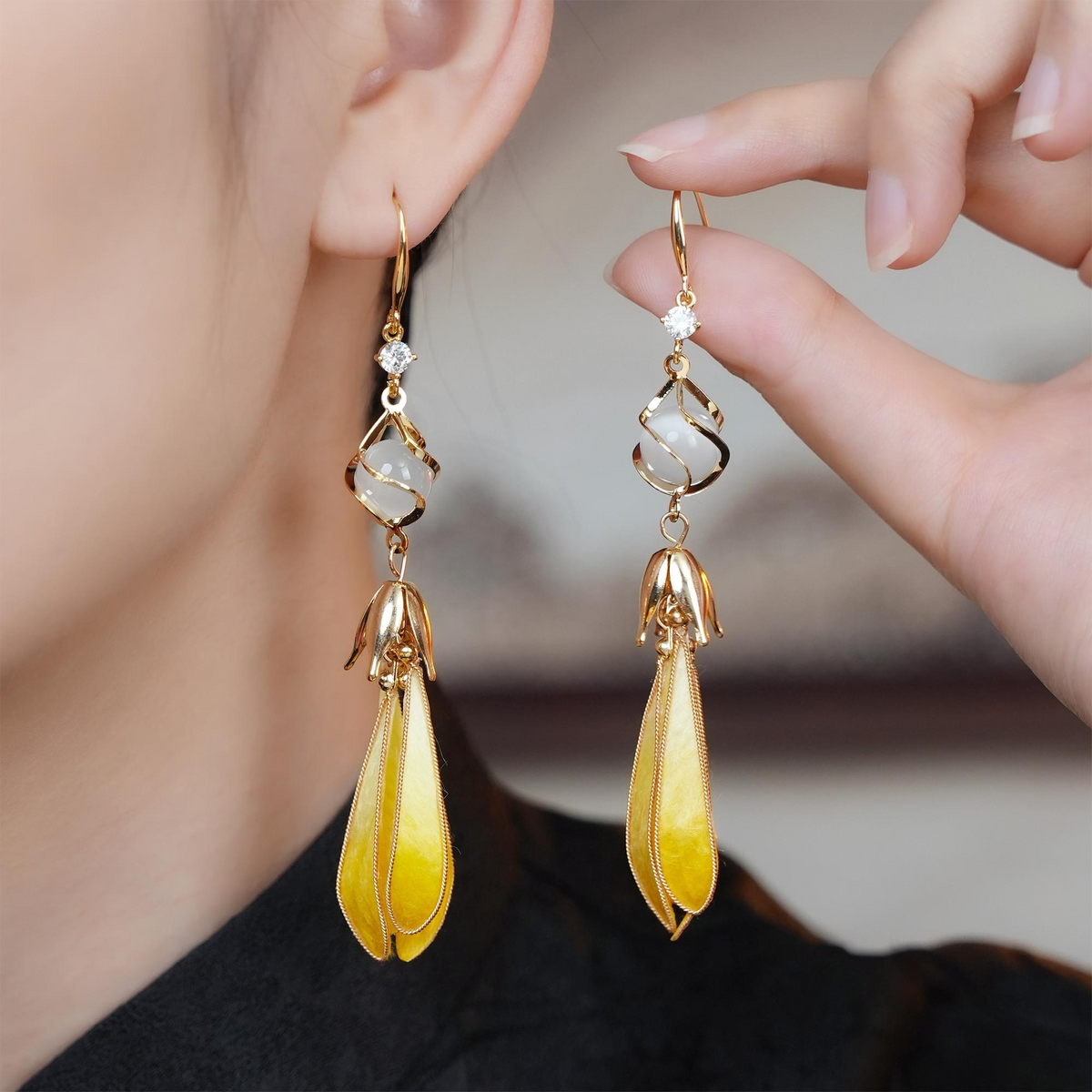 Model wearing Golden Magnolia silk velvet drop earrings and holding the matching earring