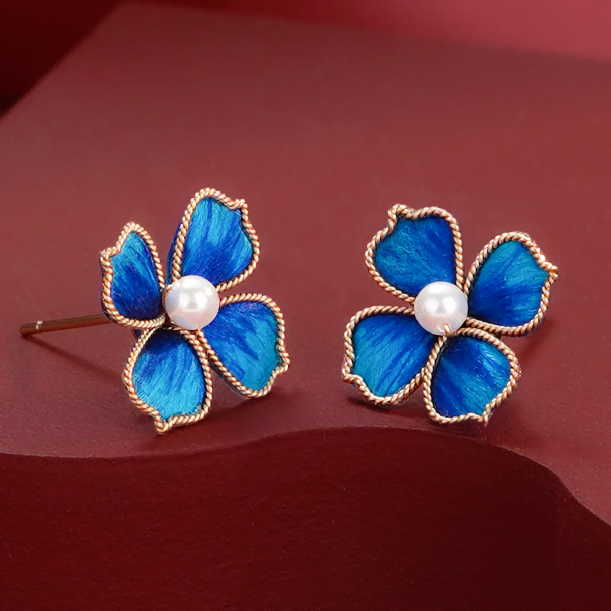 Blue Ronghua four-leaf-clover stud earrings on a red background