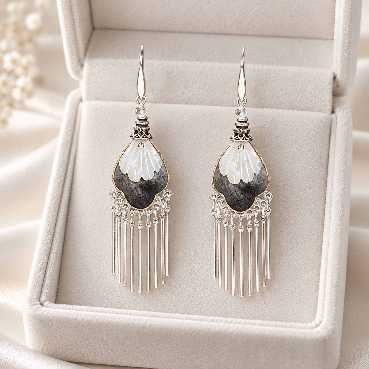 Black and ivory silk teardrops with silver-tone fringe in an ivory jewellery box