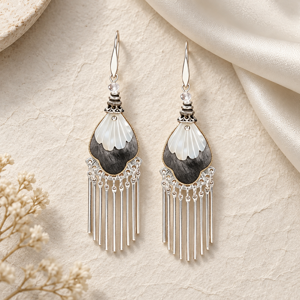 Black and ivory silk teardrops with silver-tone fringe on a cream stone surface
