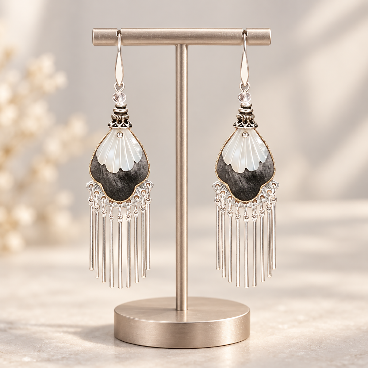 Black and ivory silk teardrops with silver-tone fringe hanging from a metal display stand