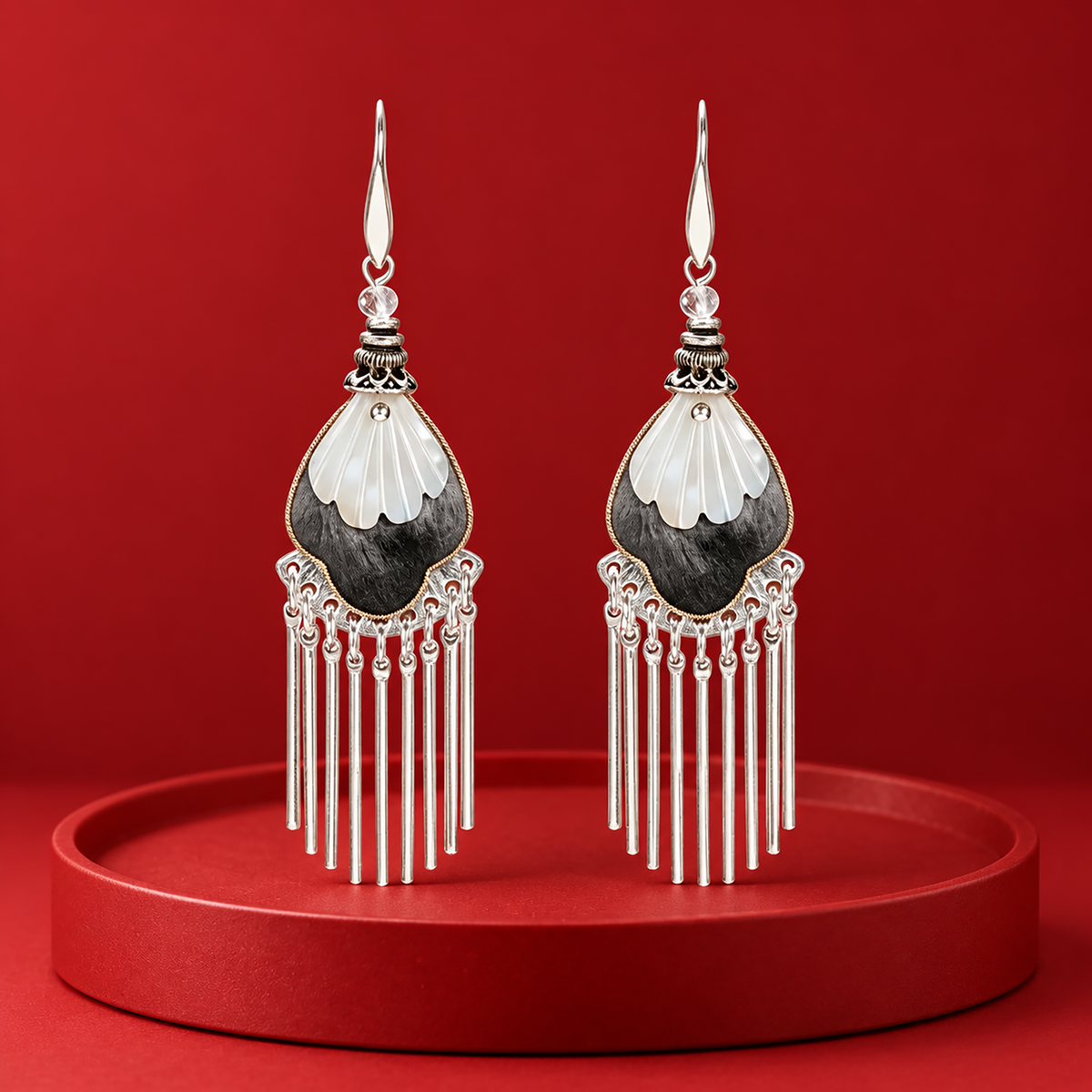 Black and ivory silk teardrops with silver-tone fringe on a red display plinth