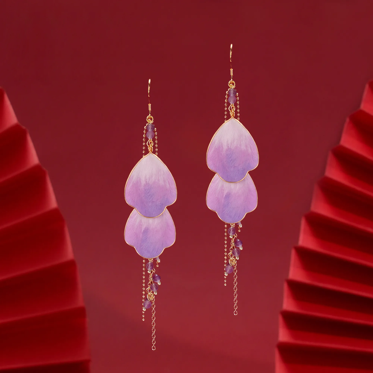 Wisteria Prelude Ronghua earrings displayed against a red sculptural background with purple silk petals and long tassels