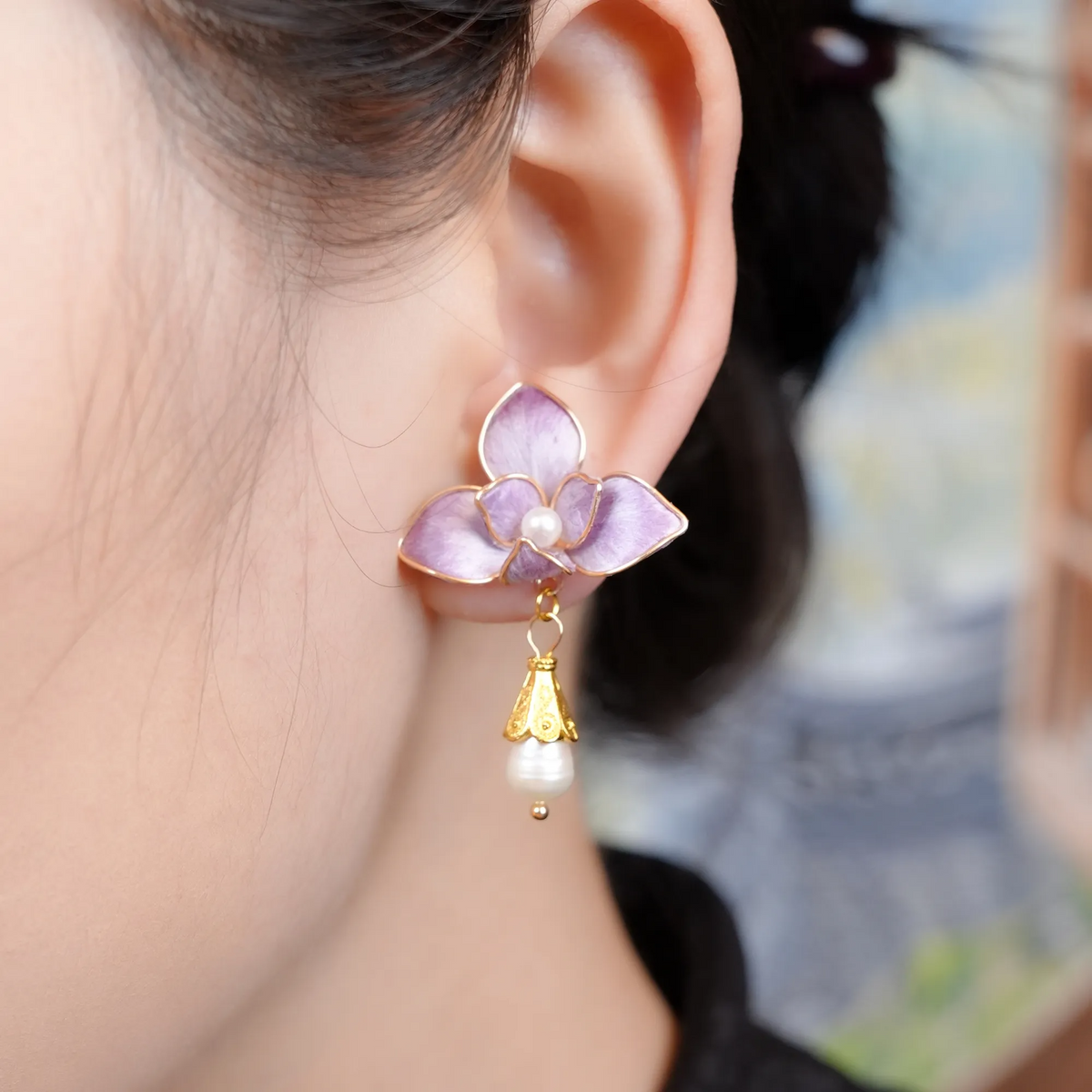 Close-up of purple butterfly orchid earrings being worn