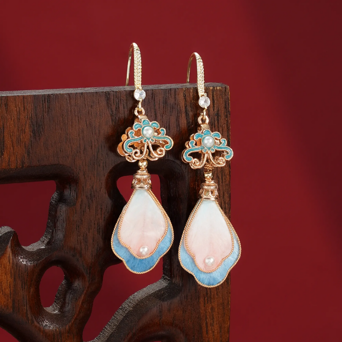 Peach blossom silk velvet earrings displayed on a wooden stand