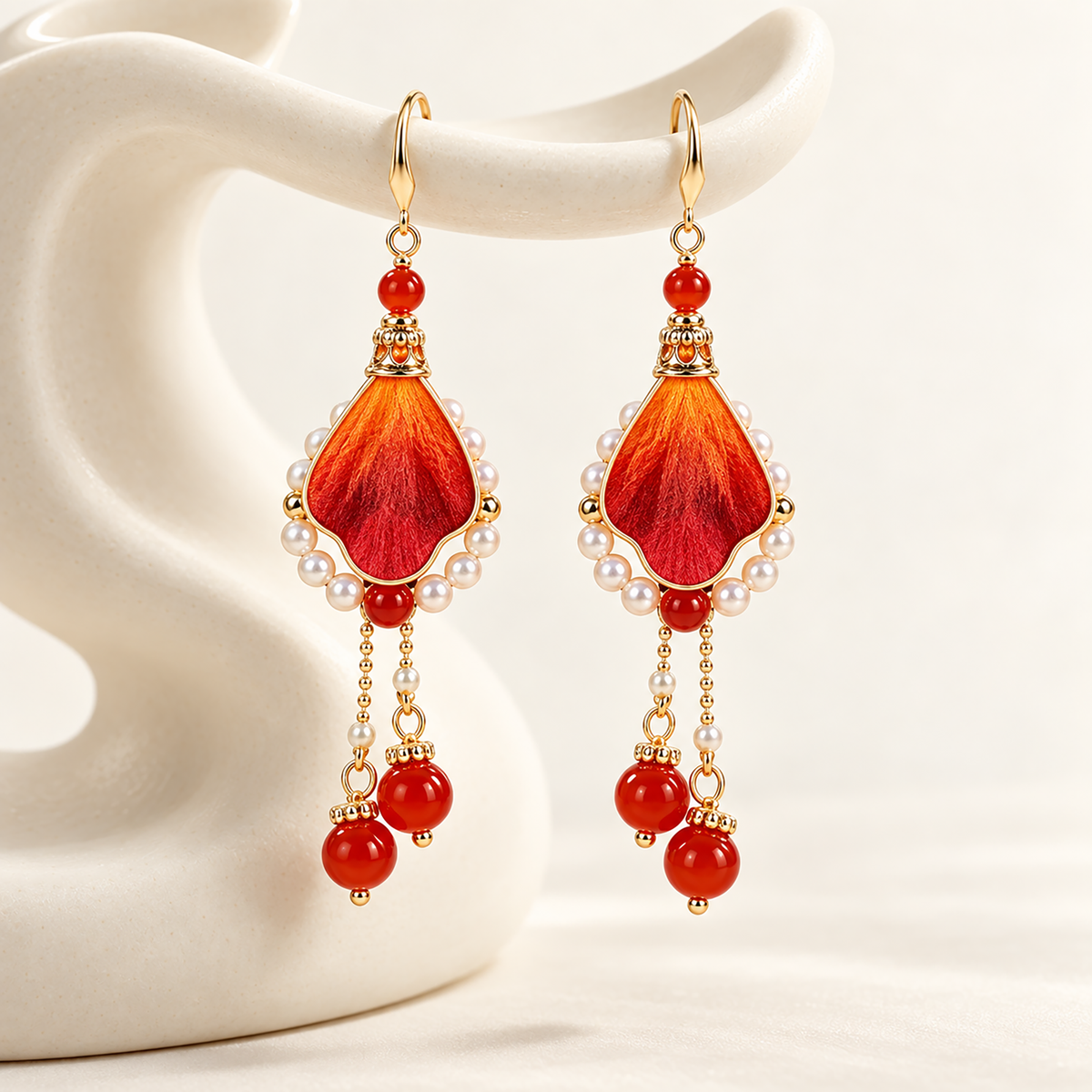 Close view of orange-crimson silk petal, pearl-effect halo and red bead drops
