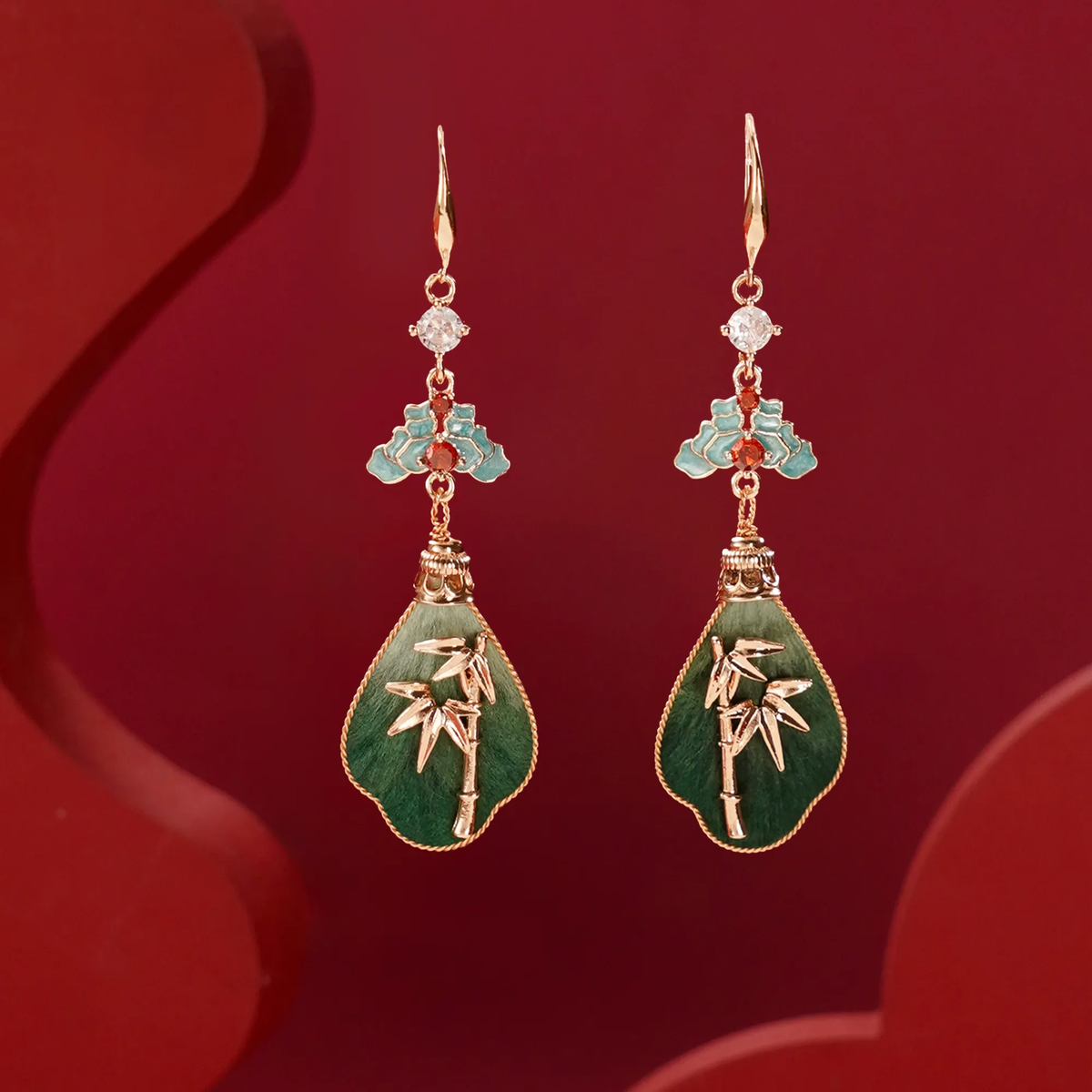 Front view of green bamboo silk velvet drop earrings on a red background