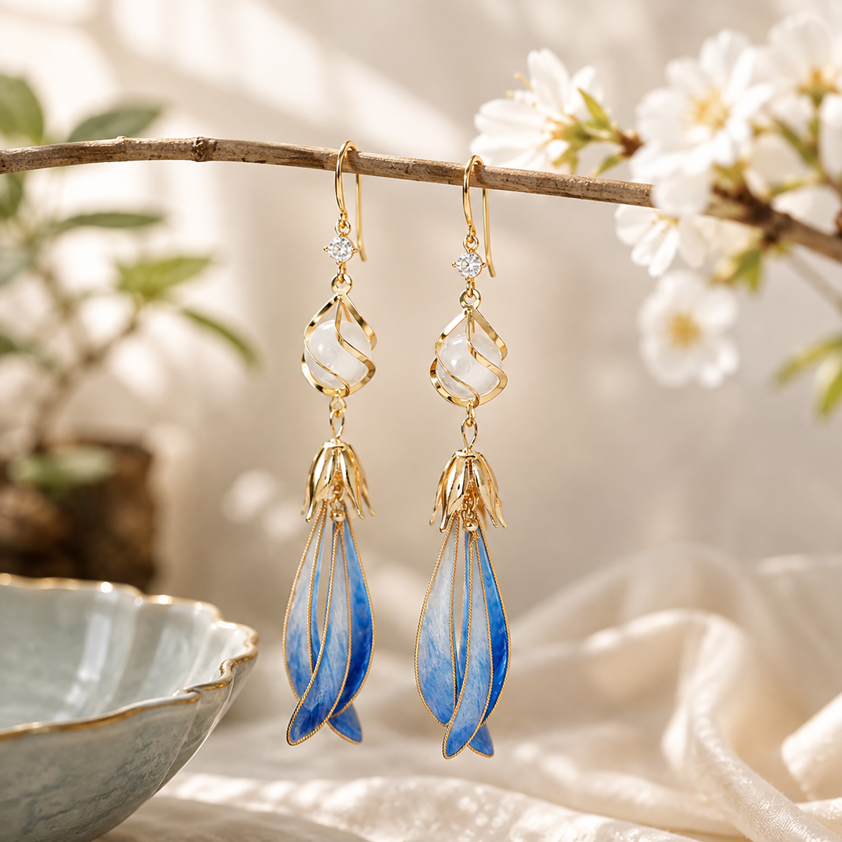 Blue magnolia silk velvet drop earrings displayed on a flowering branch