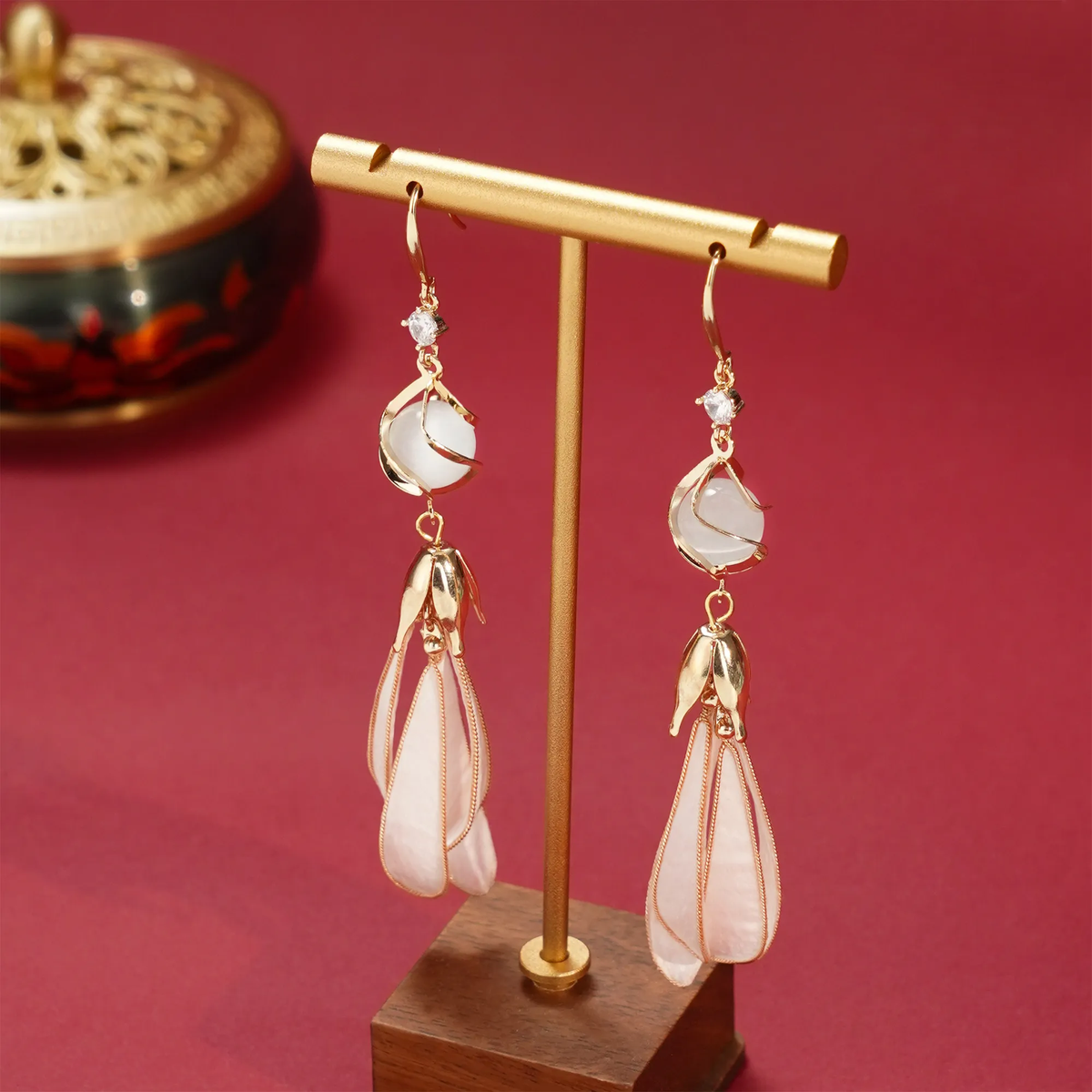 White magnolia silk velvet earrings displayed on a stand