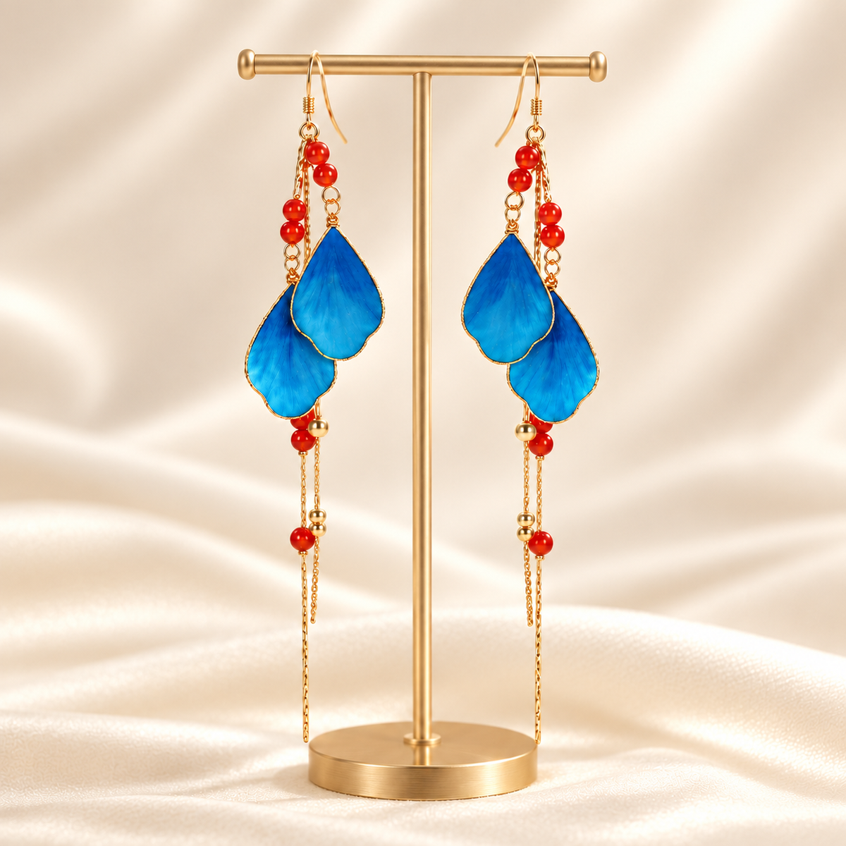 Blue petal Ronghua drop earrings with red beads on a display stand