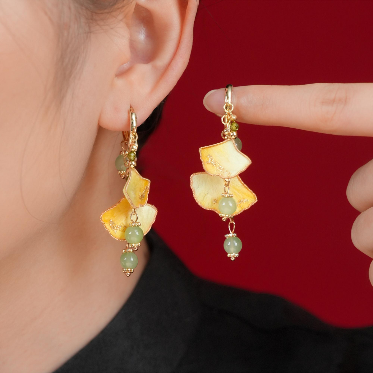 Golden ginkgo silk velvet dangle earrings shown worn and held beside the ear