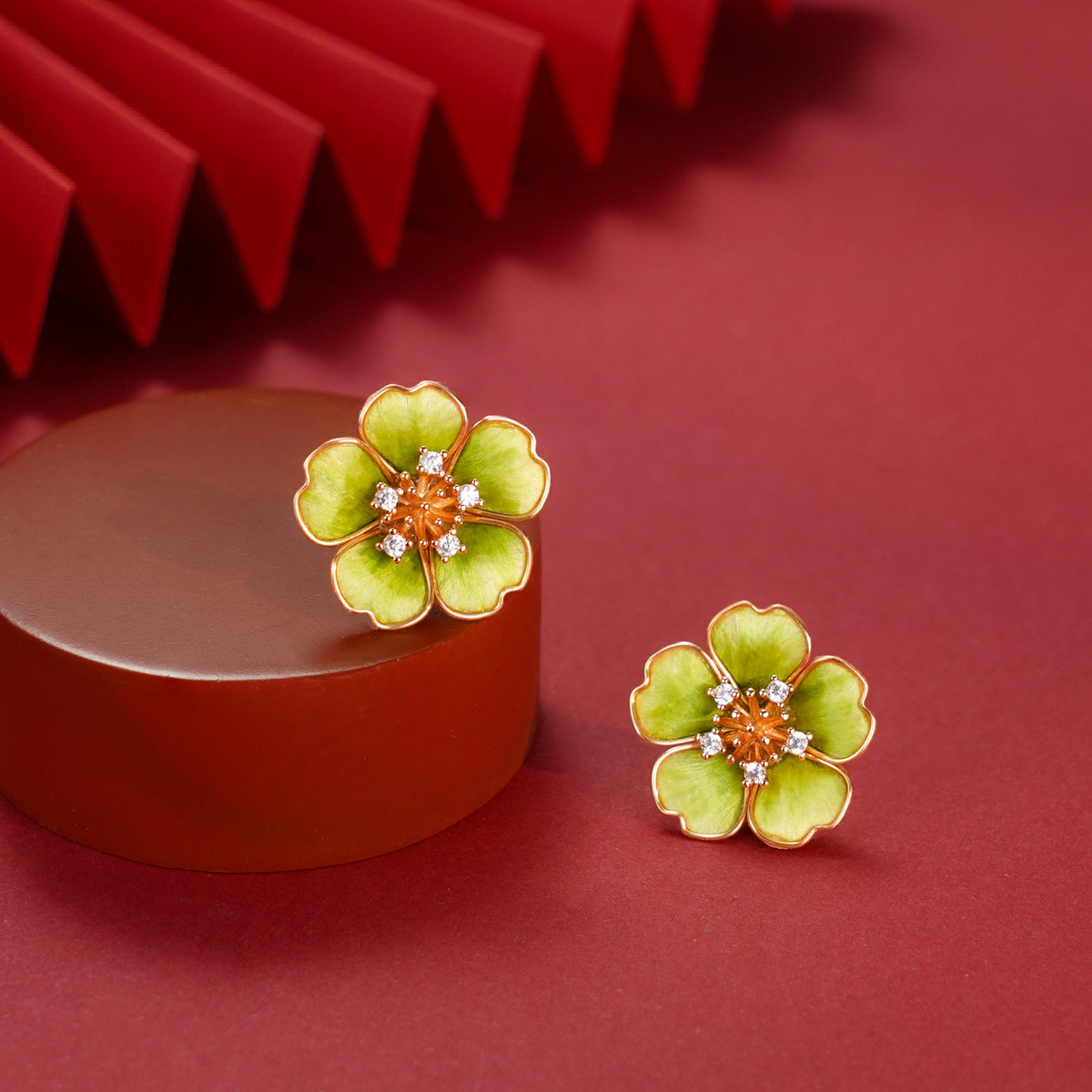 Green flower silk velvet stud earrings with clear decorative stones on a red display