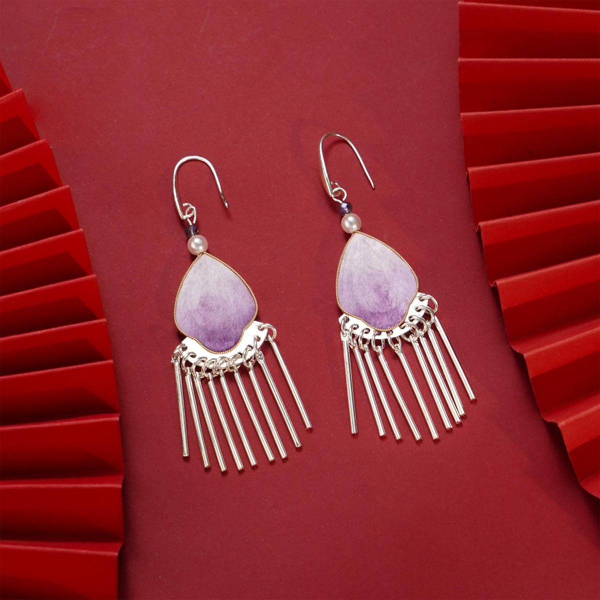 Pair of purple silk velvet tassel earrings with silver-tone fringe on red background