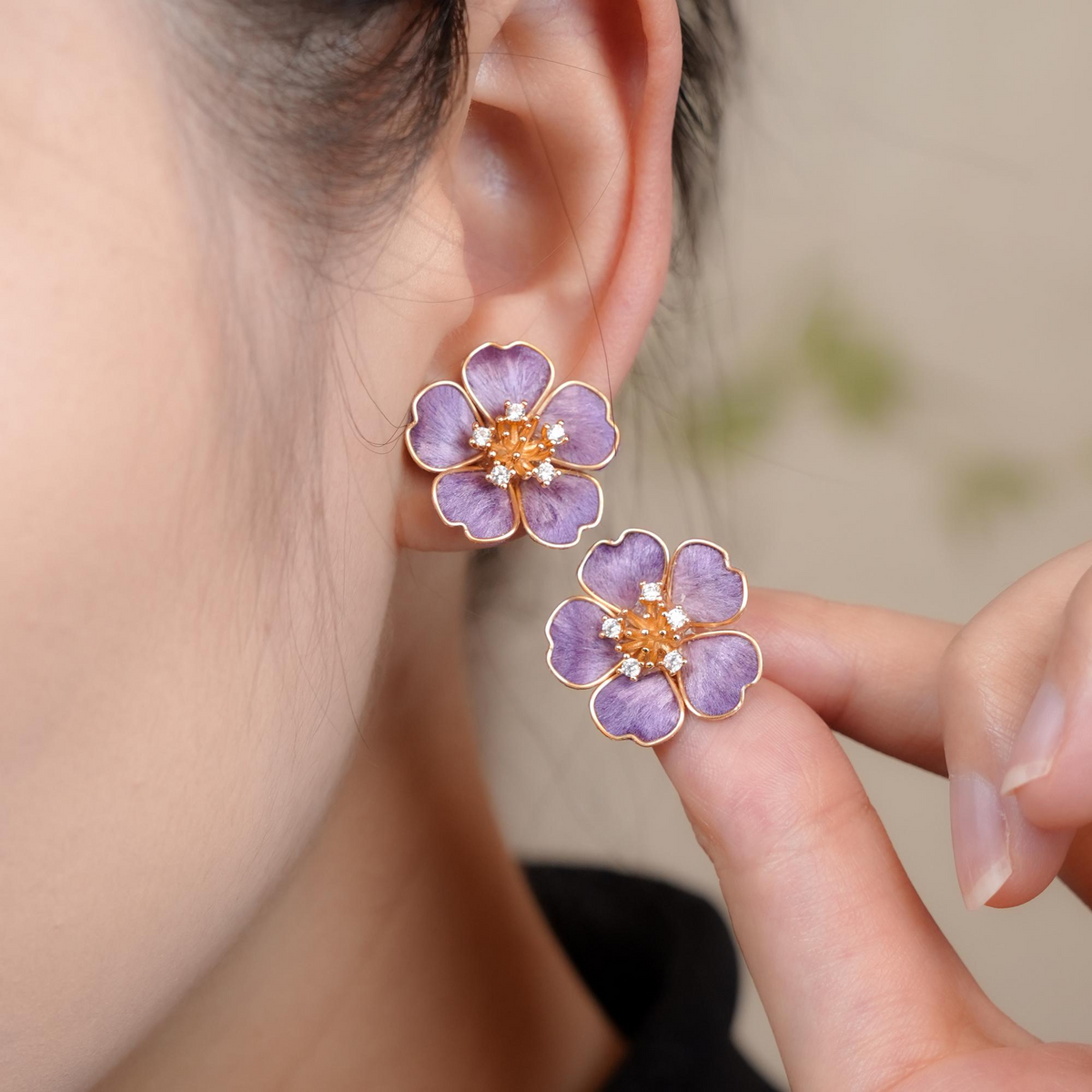 Model wearing Violet Blossom silk velvet flower stud earring and holding the matching stud