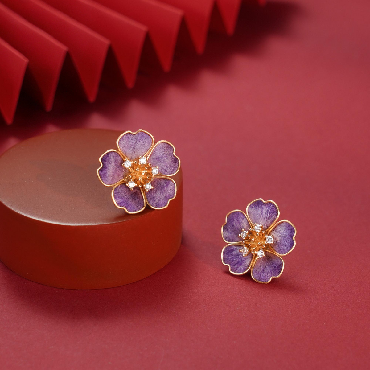 Pair of violet silk velvet flower stud earrings displayed on a red pedestal