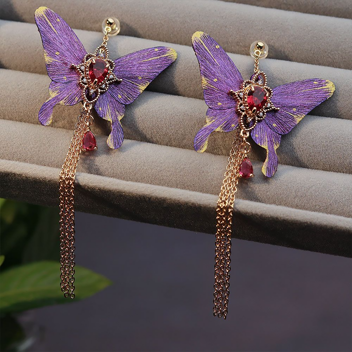 Close view of hand-shaped purple silk butterfly wings and gold-tone details