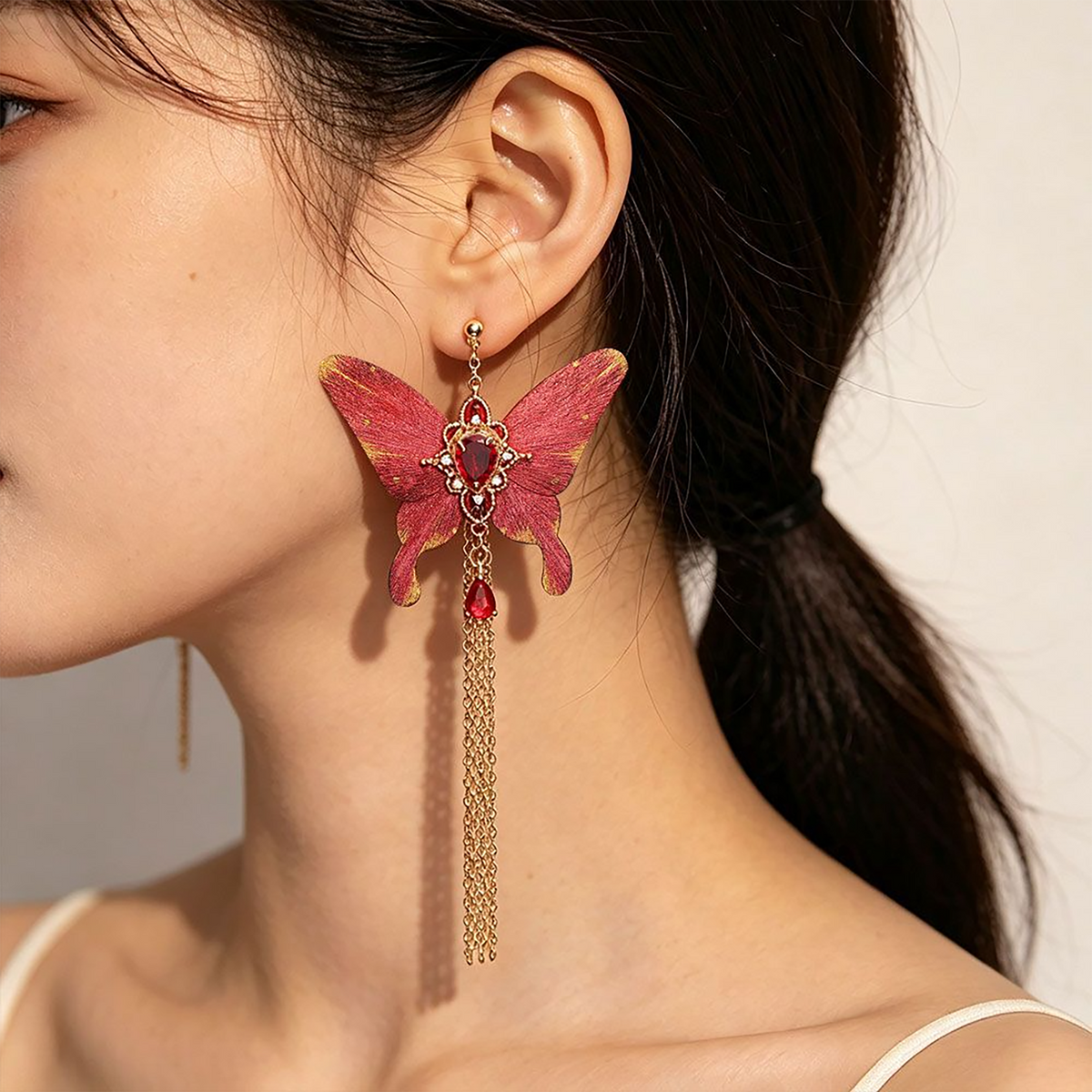 Model wearing a red butterfly silk velvet tassel earring with crystal accents