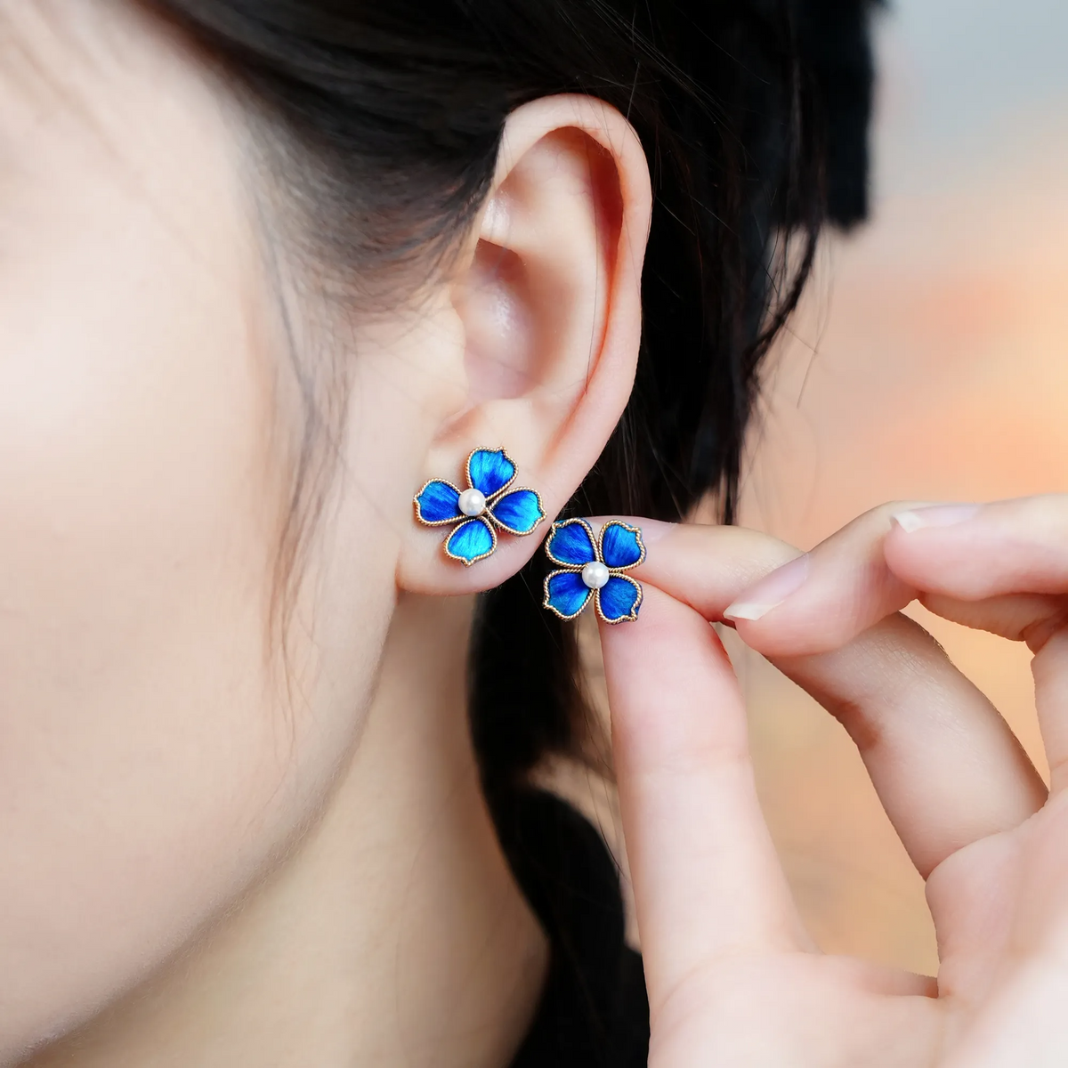 Model wearing and holding Blue Four-Leaf Clover Ronghua Stud Earrings