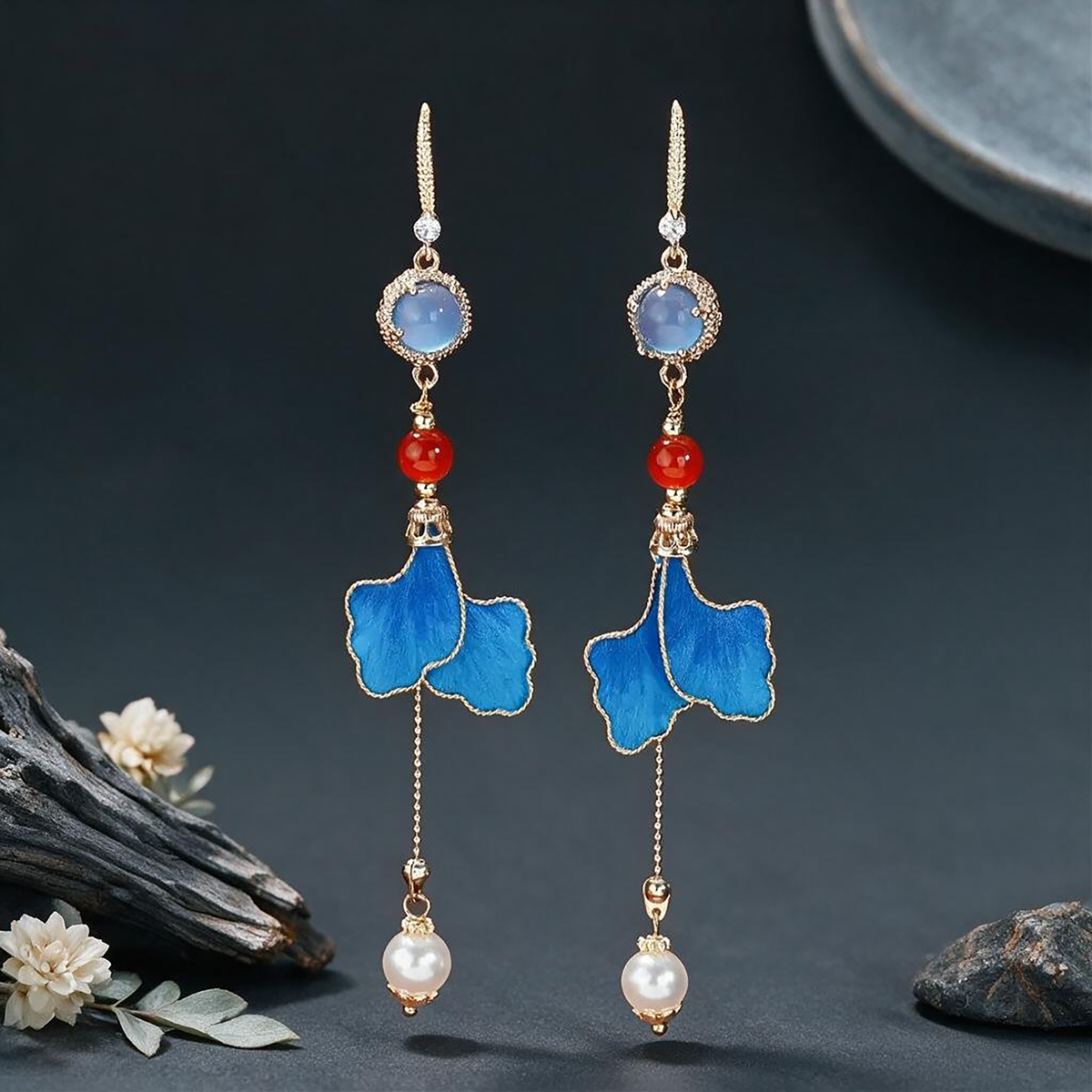 Handmade blue leaf Ronghua drop earrings with red and blue bead accents on a dark background