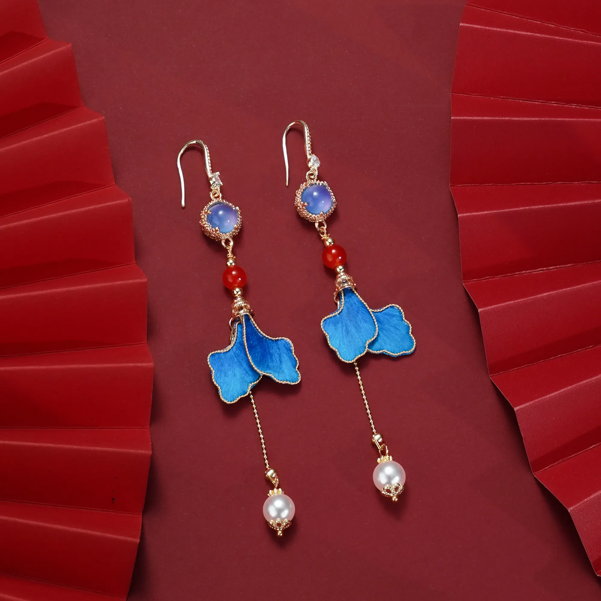 Long blue leaf Ronghua earrings laid flat with bead and suspended chain details