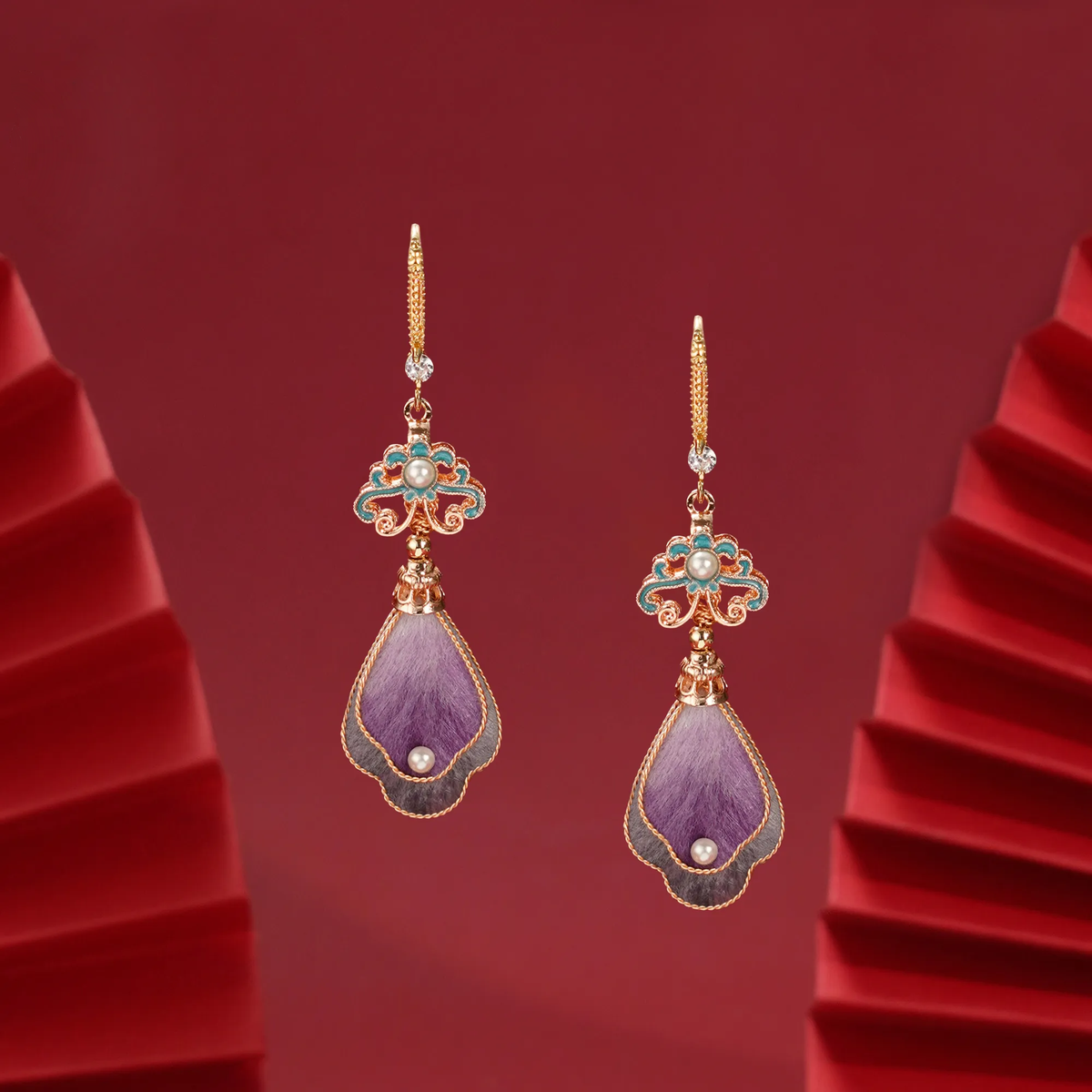 Angled view of Twilight Cloud Mountain earrings on a folded red background
