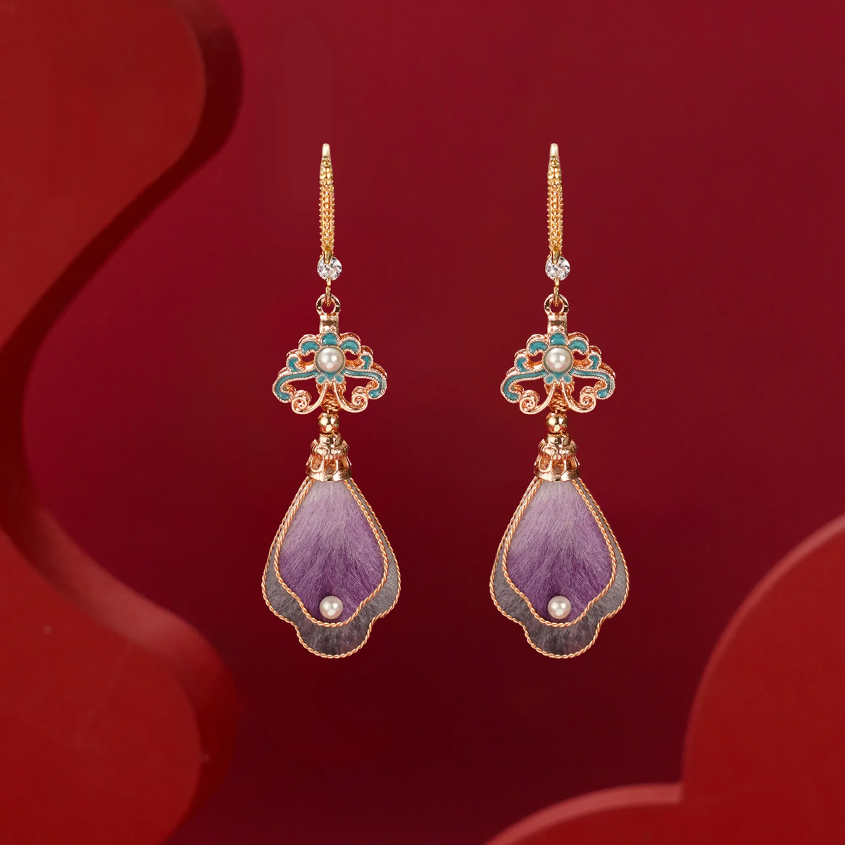 Front view of lavender and turquoise silk velvet drop earrings on a red background