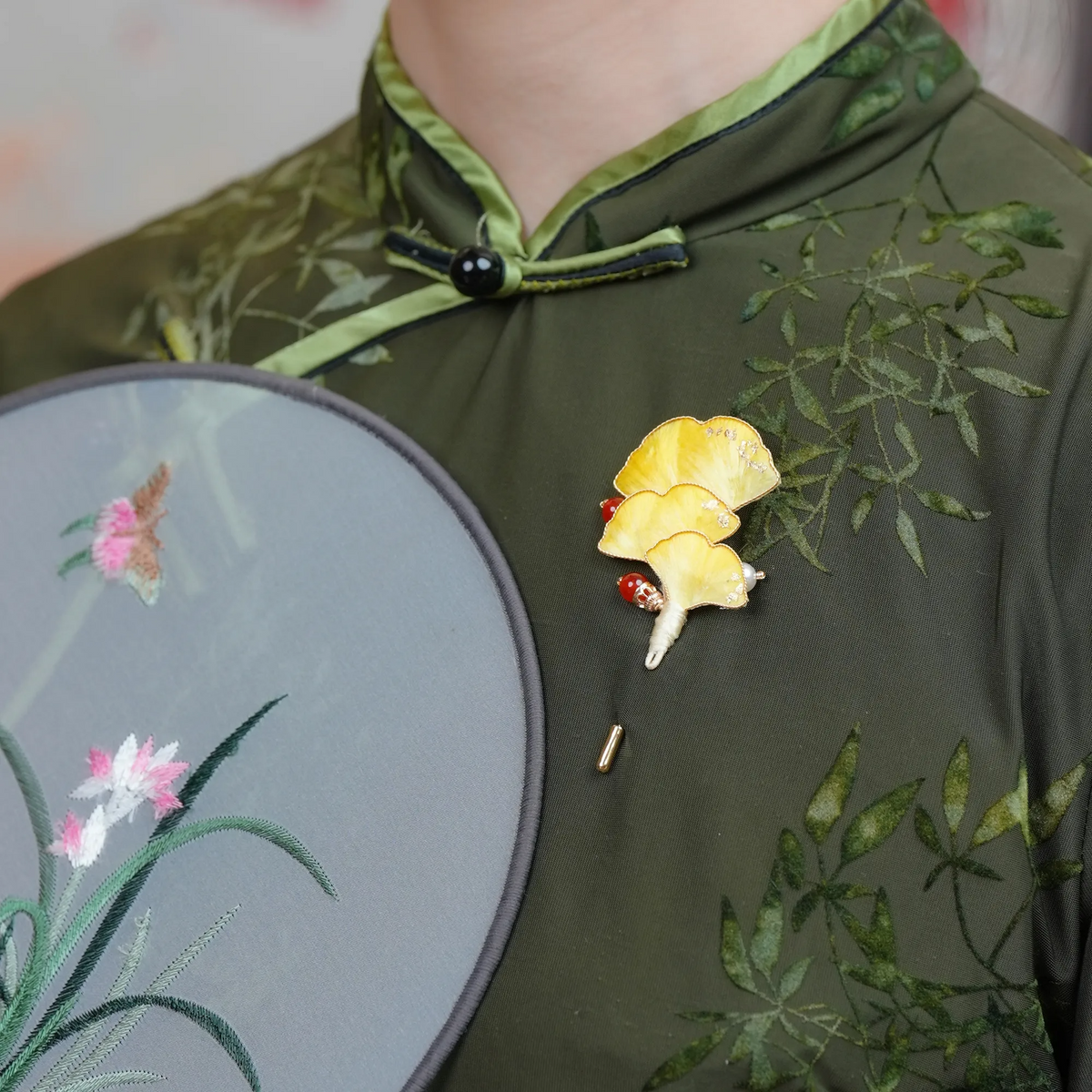 Model wearing Ginkgo Ronghua wirework stickpin brooch with a dark green embroidered blouse