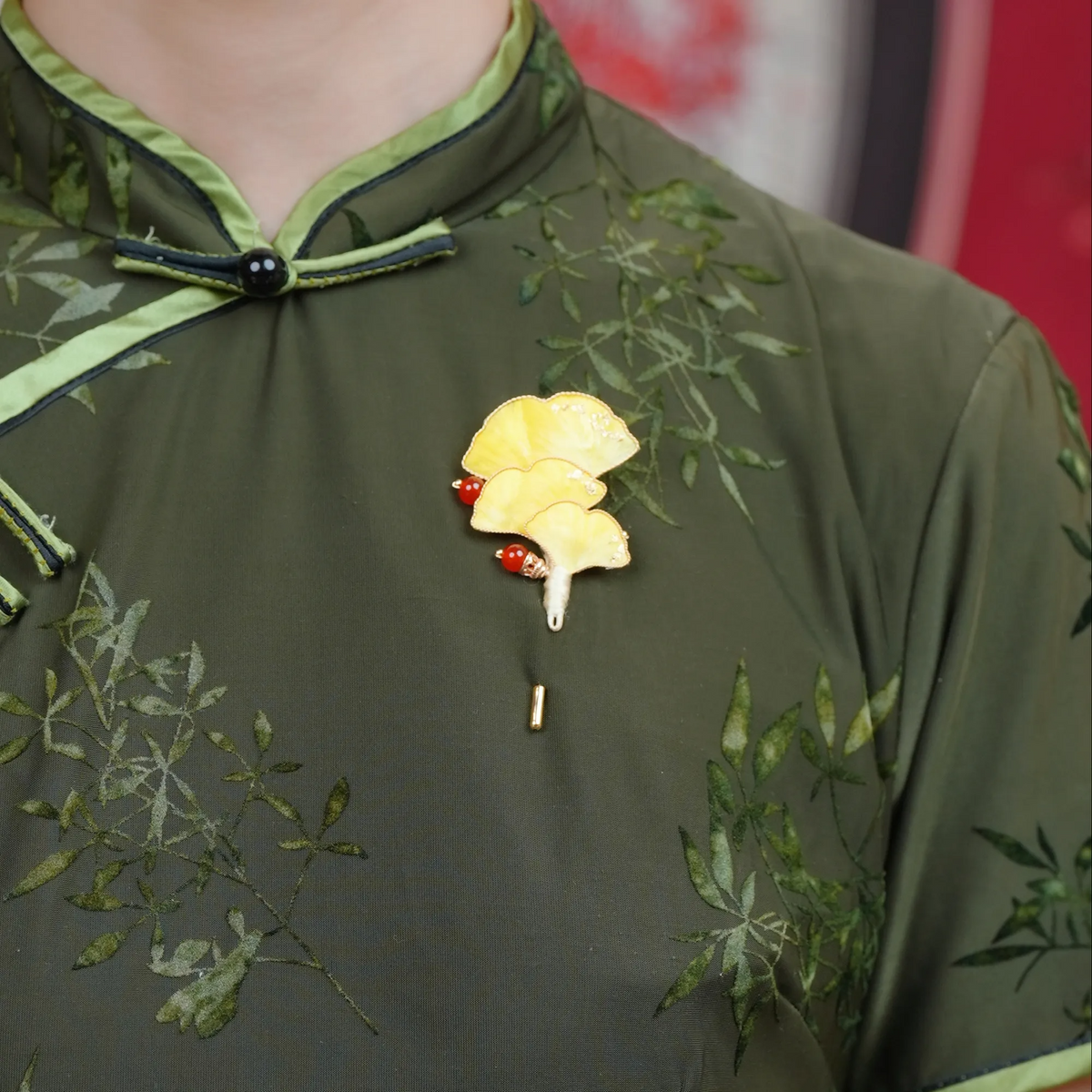 Close view of Ginkgo Ronghua wirework stickpin brooch worn on a dark green embroidered blouse