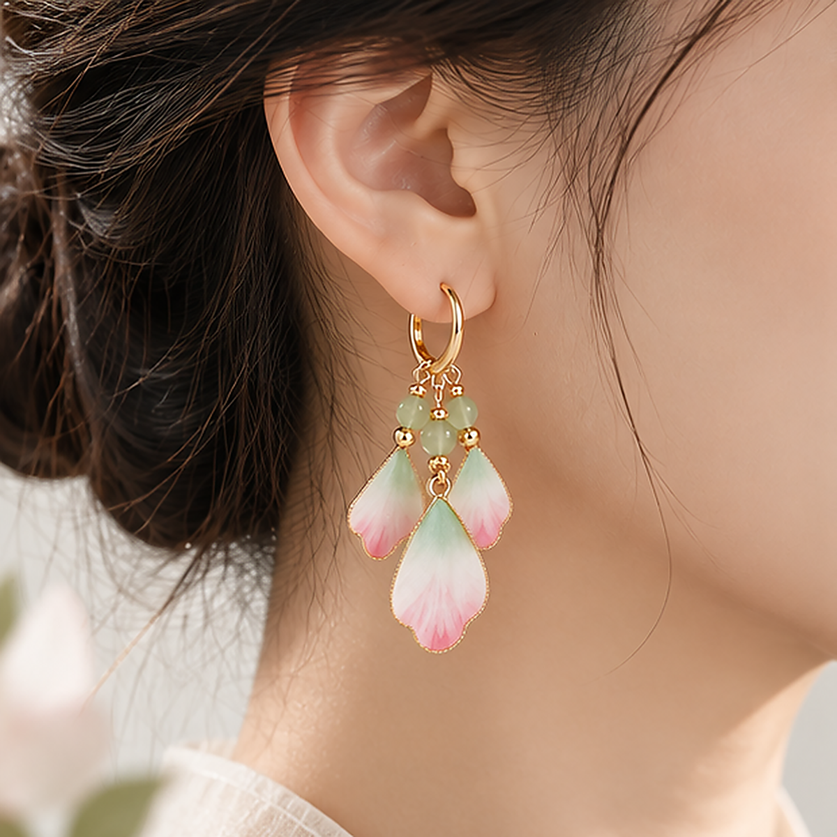 Three pink, ivory and green silk petals suspended from each gold-tone hoop worn in a close-up side view