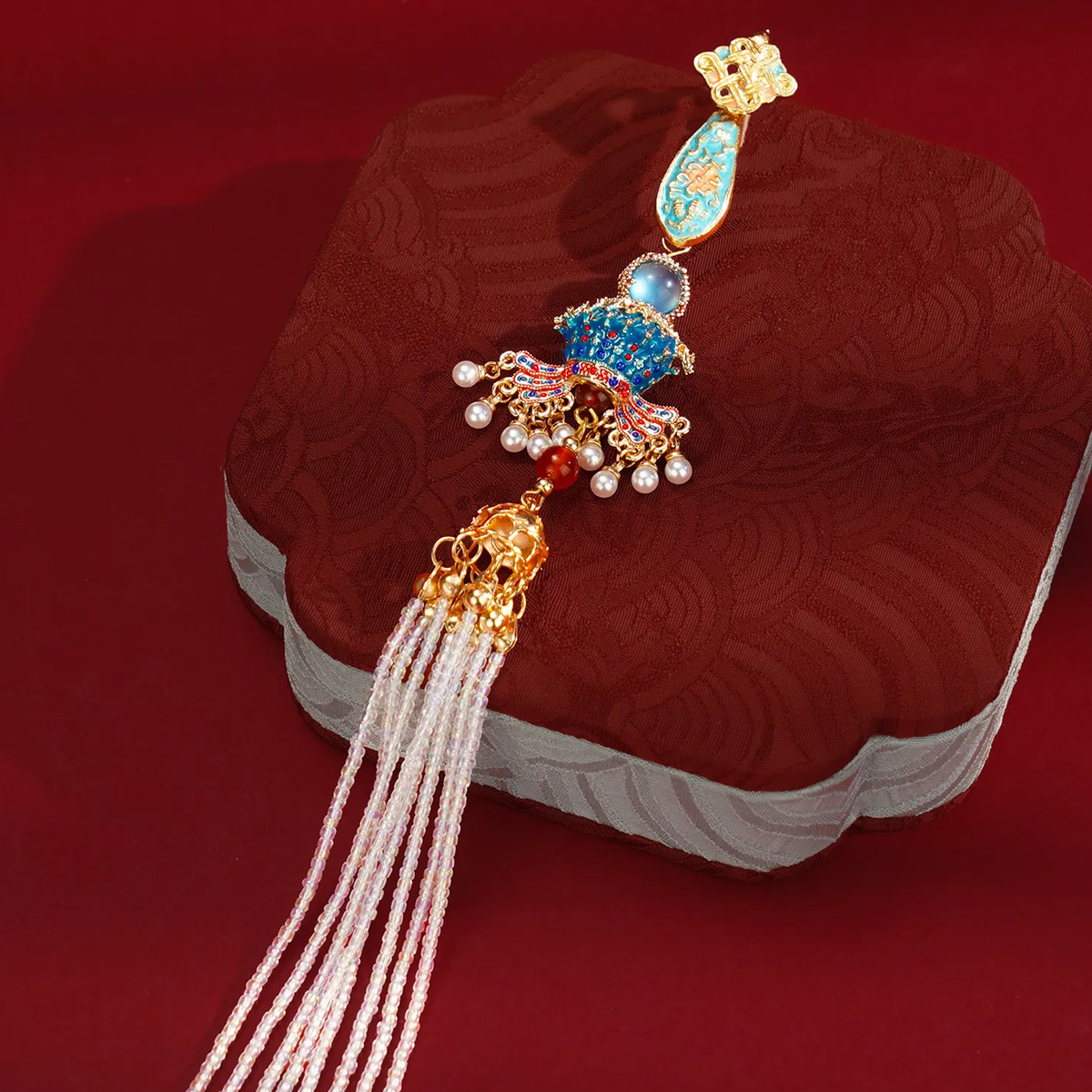 Nine Dragons and Nine Phoenixes Qipao Brooch displayed on a red fabric box