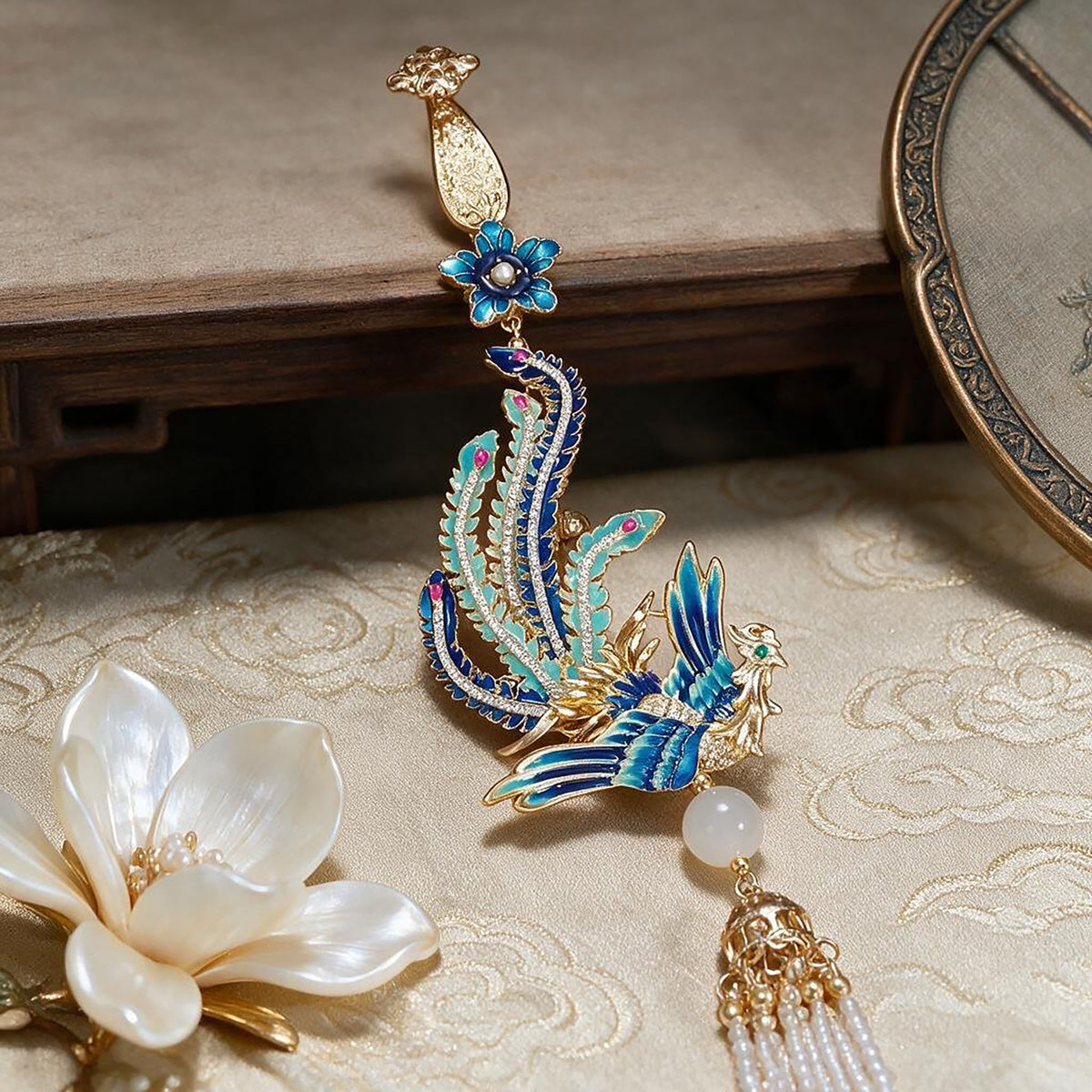 Phoenix Arrival Brooch with tassel displayed on a patterned surface