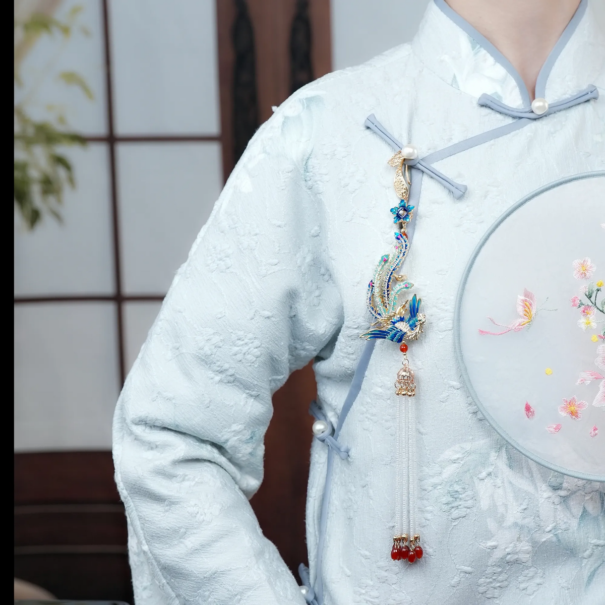 Model wearing Phoenix Arrival Brooch on a white traditional-inspired garment