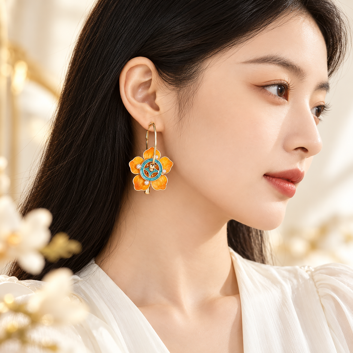 Orange silk flowers with teal circular centres on gold-tone hoops worn beside the face