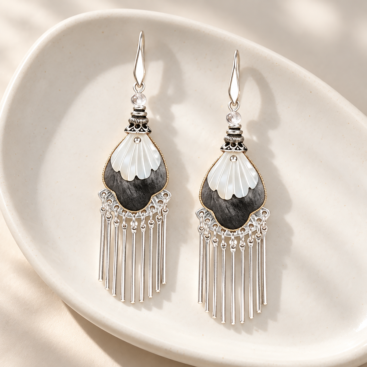 Black and ivory silk teardrops with silver-tone fringe on a white dish
