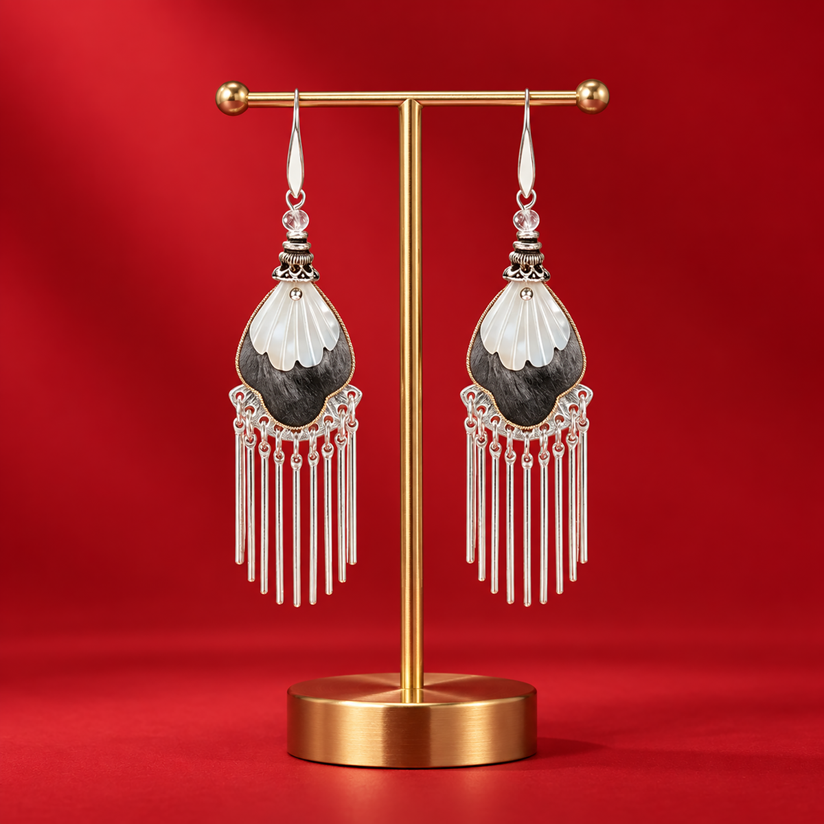 Black and ivory silk teardrops with silver-tone fringe on a gold-tone stand against red fabric