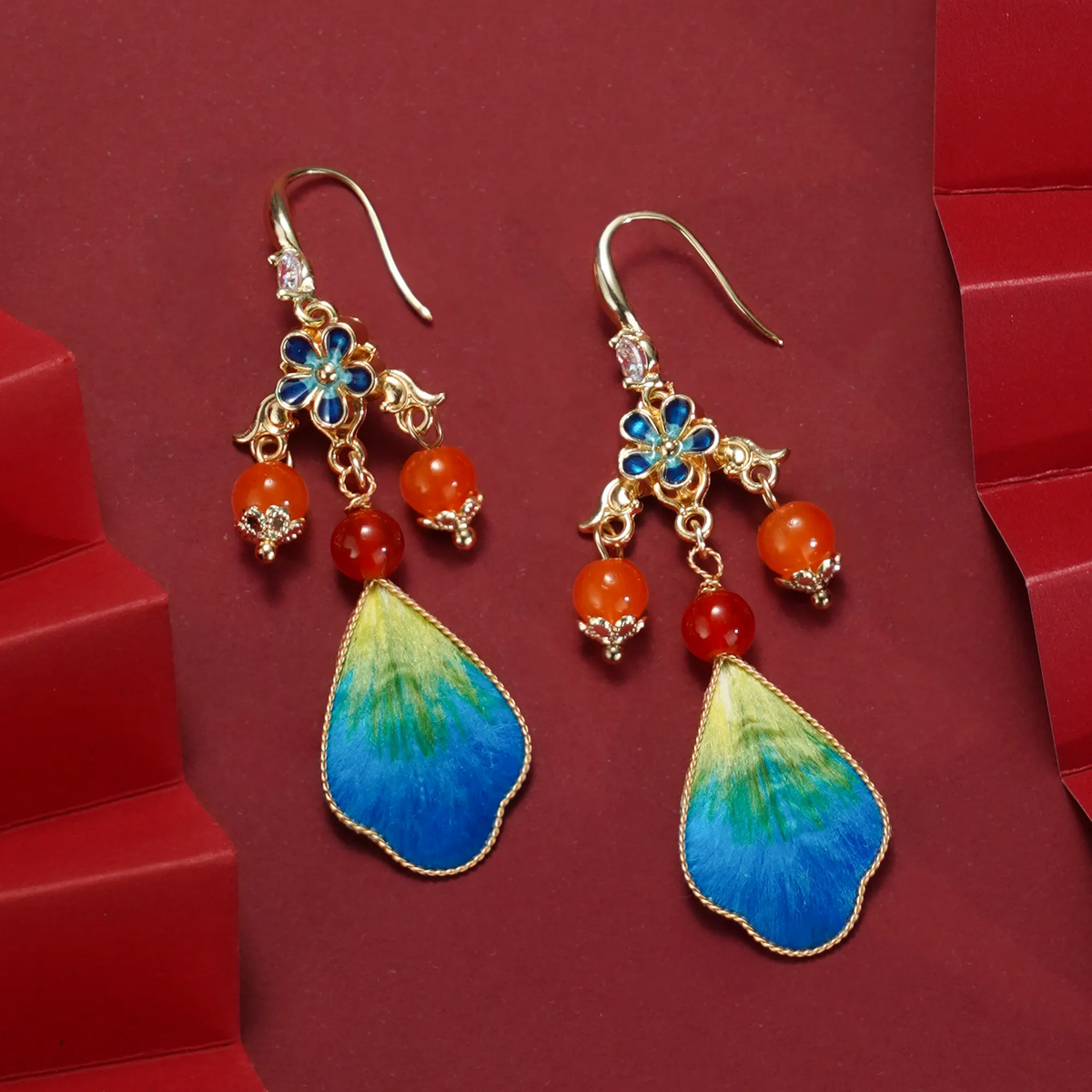 Pair of landscape-inspired Ronghua drop earrings on red background