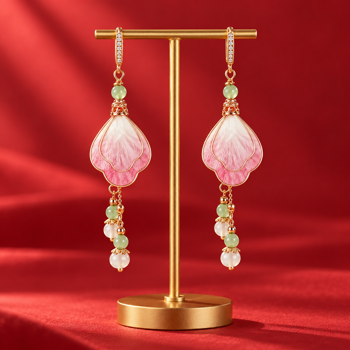 Layered pink and ivory silk petals with green and white bead drops on a stand against red fabric